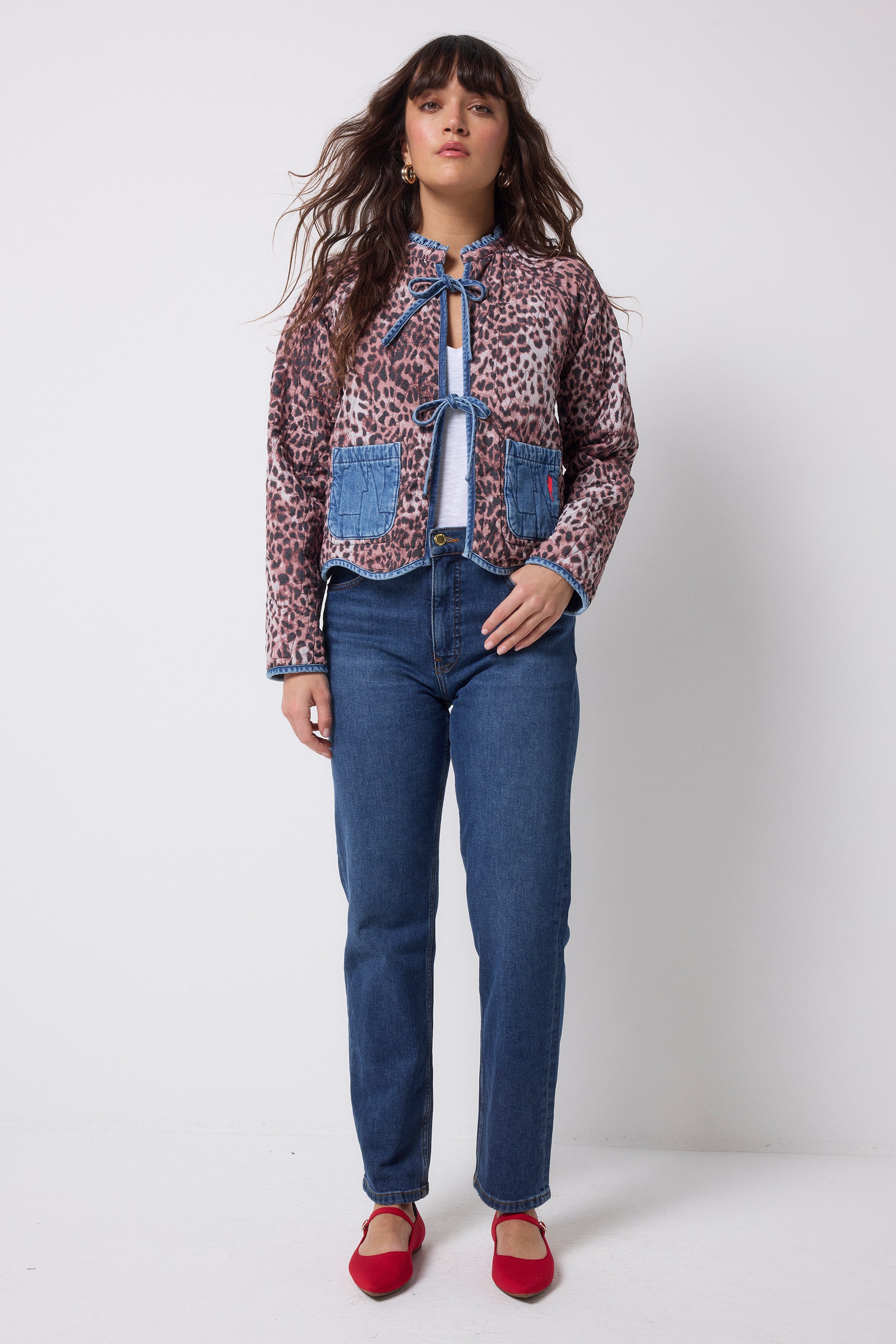 Scamp and Dude Denim Quilted Reversible Jacket | Model wearing a pair of dark blue jeans with a reversible cheetah print denim quilted jacket that ties at the front.