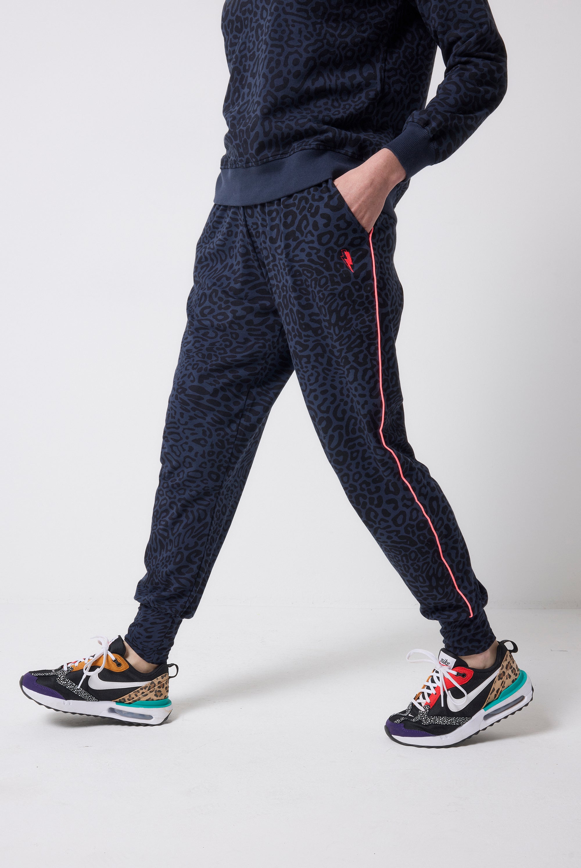 Scamp and Dude Navy with Black Leopard Ray Slouch Joggers | Model wearing navy leopard ray print joggers with a matching sweatshirt and colourful trainers.