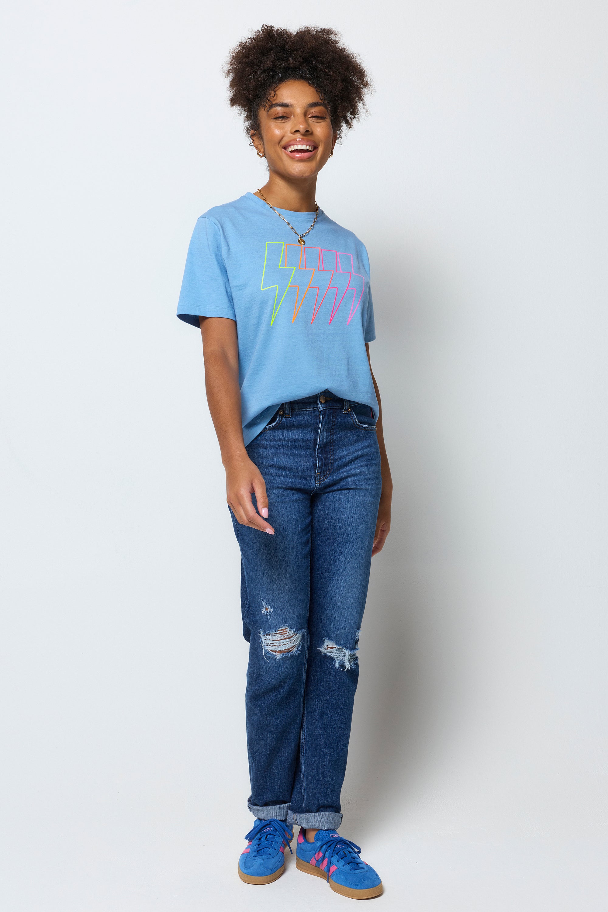 Scamp and Dude Blue Multi Neon Bolt Classic T-Shirt | Model wearing a blue bolt t-shirt with a pair of blue distressed jeans.