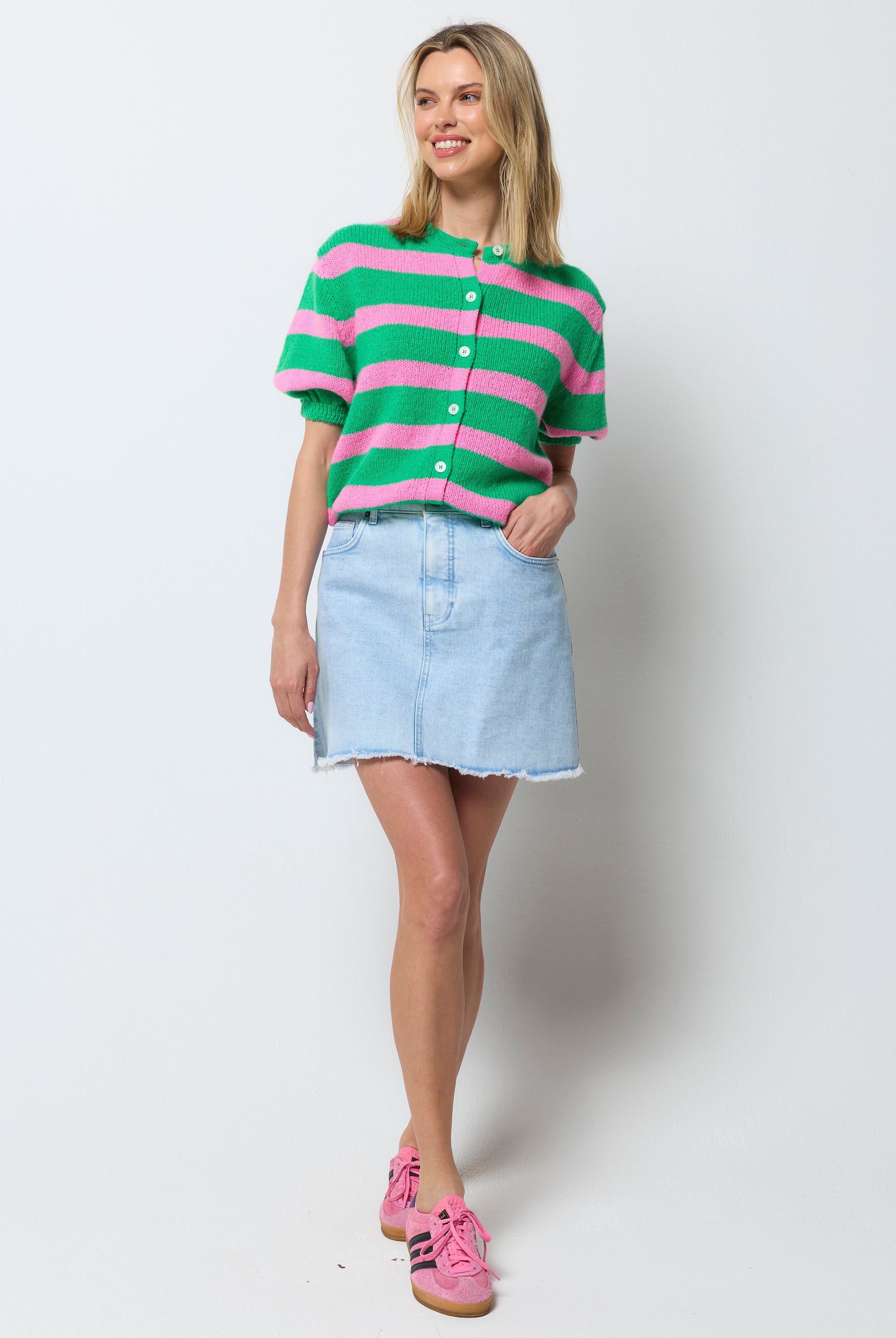 Scamp and Dude Ice Blue Wash Denim Mini Skirt | Model wearing a pink and green strip cardigan with a ice blue denim mini skirt.