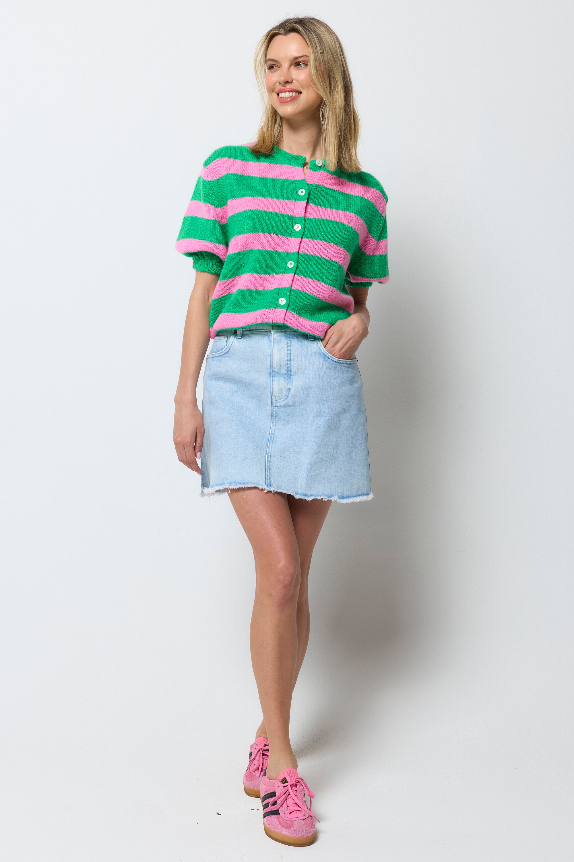 Scamp and Dude Ice Blue Wash Denim Mini Skirt | Model wearing a pink and green strip cardigan with a ice blue denim mini skirt.