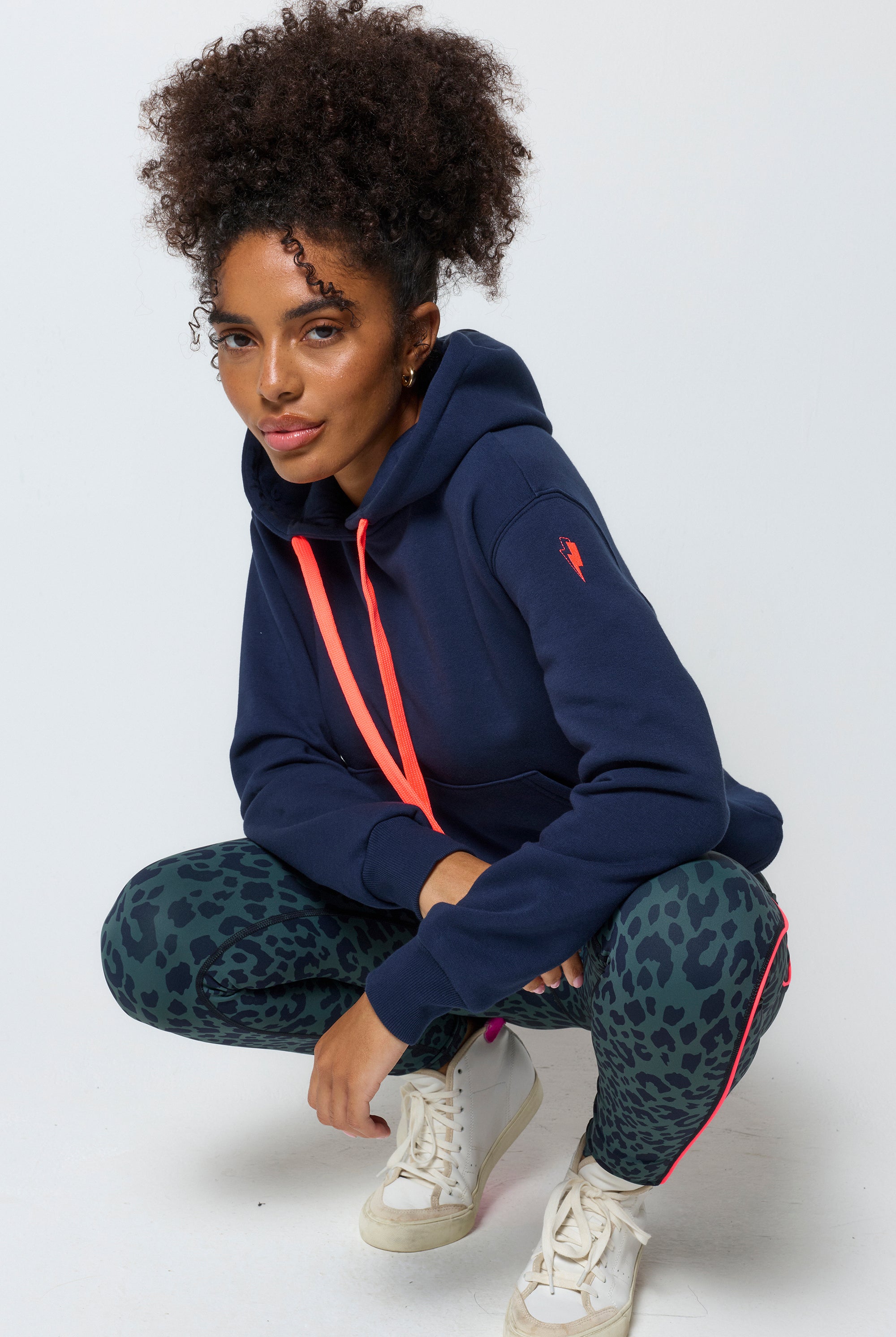 Scamp and Dude Navy Embroidered Logo Ultimate Hoodie | Model wearing dark navy hoodie with embroidered Scamp & Dude logo on the back. Worn with khaki leopard print leggings.