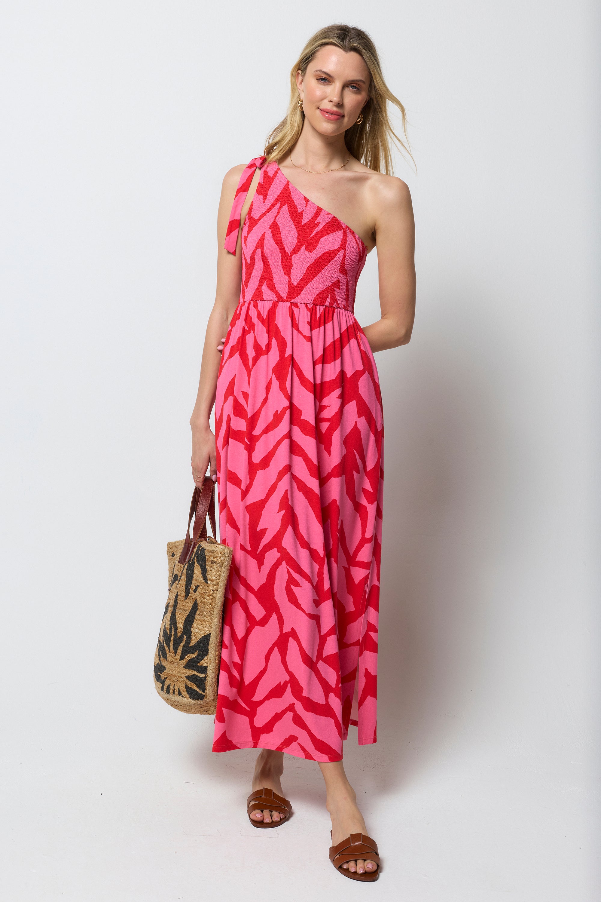 Scamp & Dude Red and Pink Zebra One Shoulder Maxi Dress | Model wear a one should maxi dress in a red and print zebra print. Holding a neutral straw bag with sunstar print.