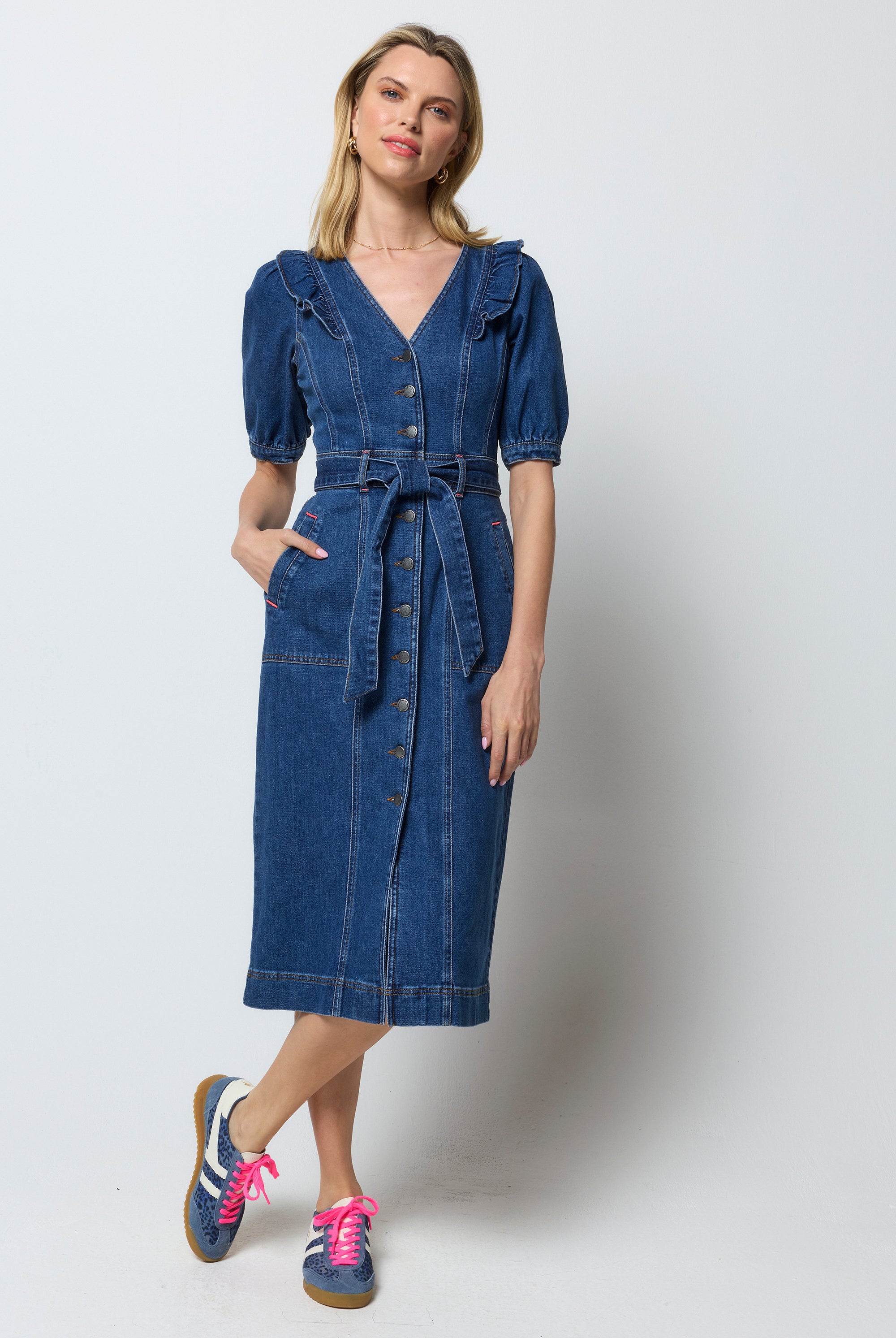 Scamp and Dude Indigo Frill Sleeve Midi Denim Dress | Model wearing a dark blue denim dress with frill detail on the should and a tie waist belt.
