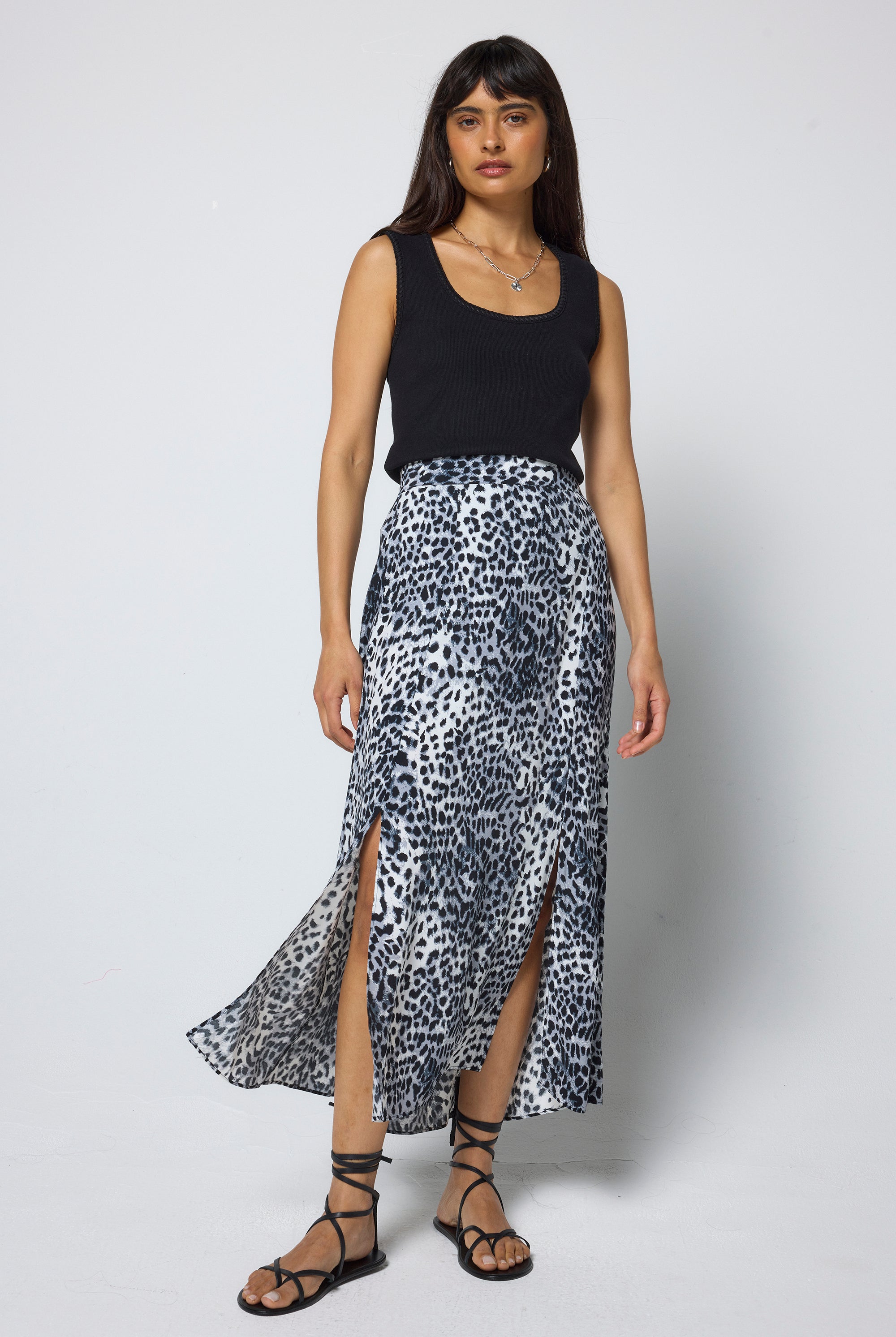 Scamp & Dude Grey with White and Black Cheetah Split Front Skirt | Model wearing a black sleeveless top and cheetah print midi skirt on a white background.