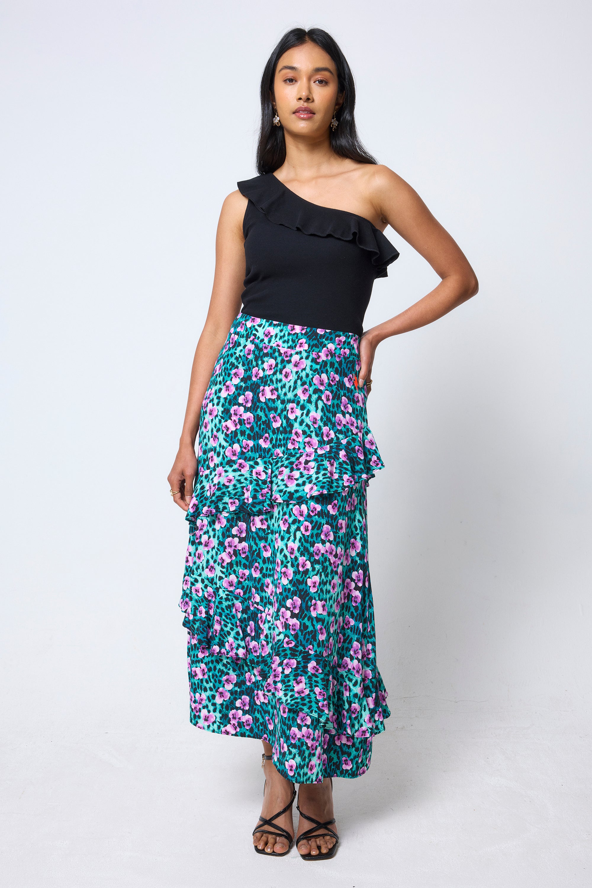 Scamp & Dude Black One Shoulder Frill Top | Model wearing a black one-shoulder top and floral tiered skirt with black heels.