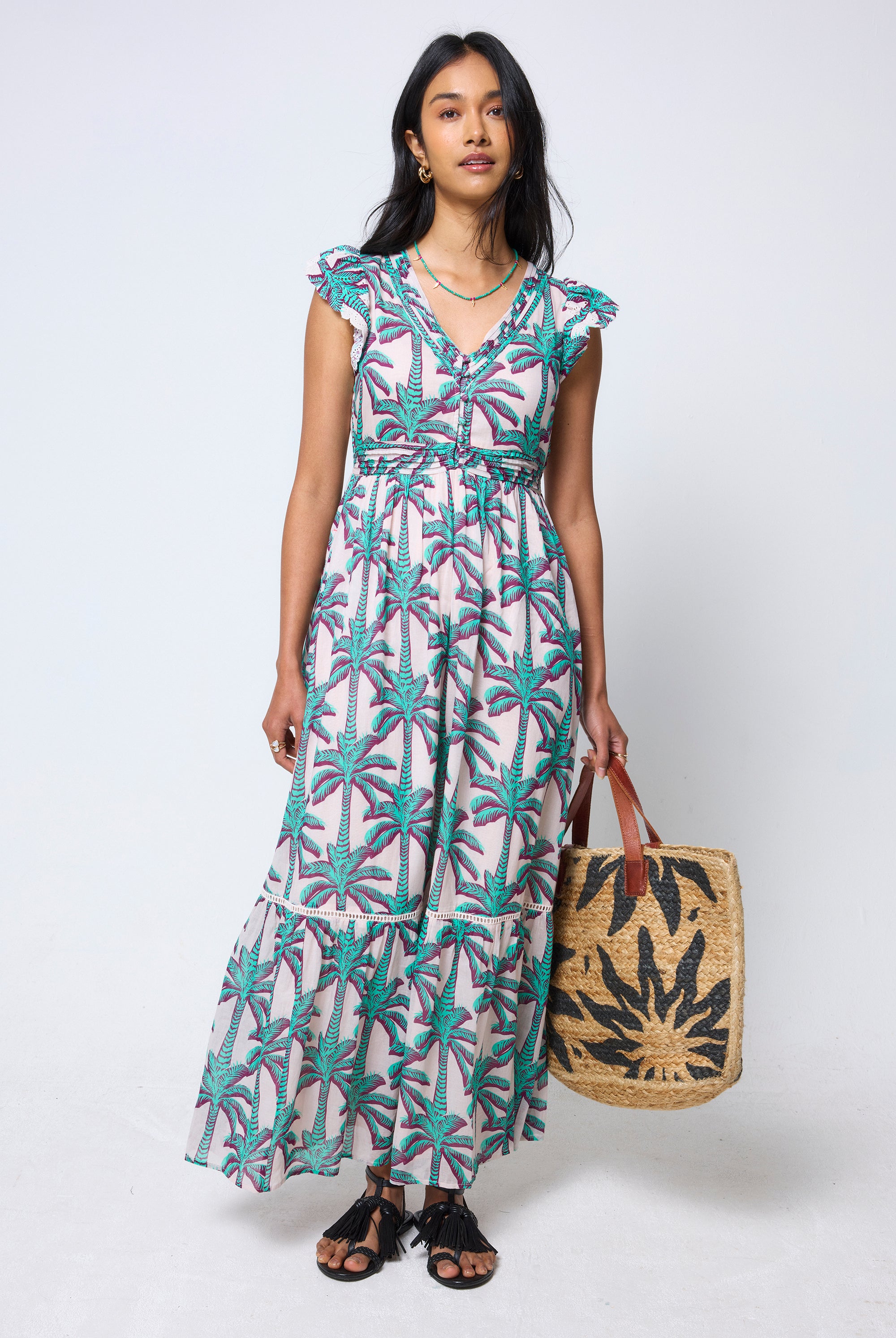 Scamp & Dude Cream with Green Shadow Palm Broderie Sleeve Pintuck Maxi Dress | Model wearing a palm tree patterned dress holding a woven bag.