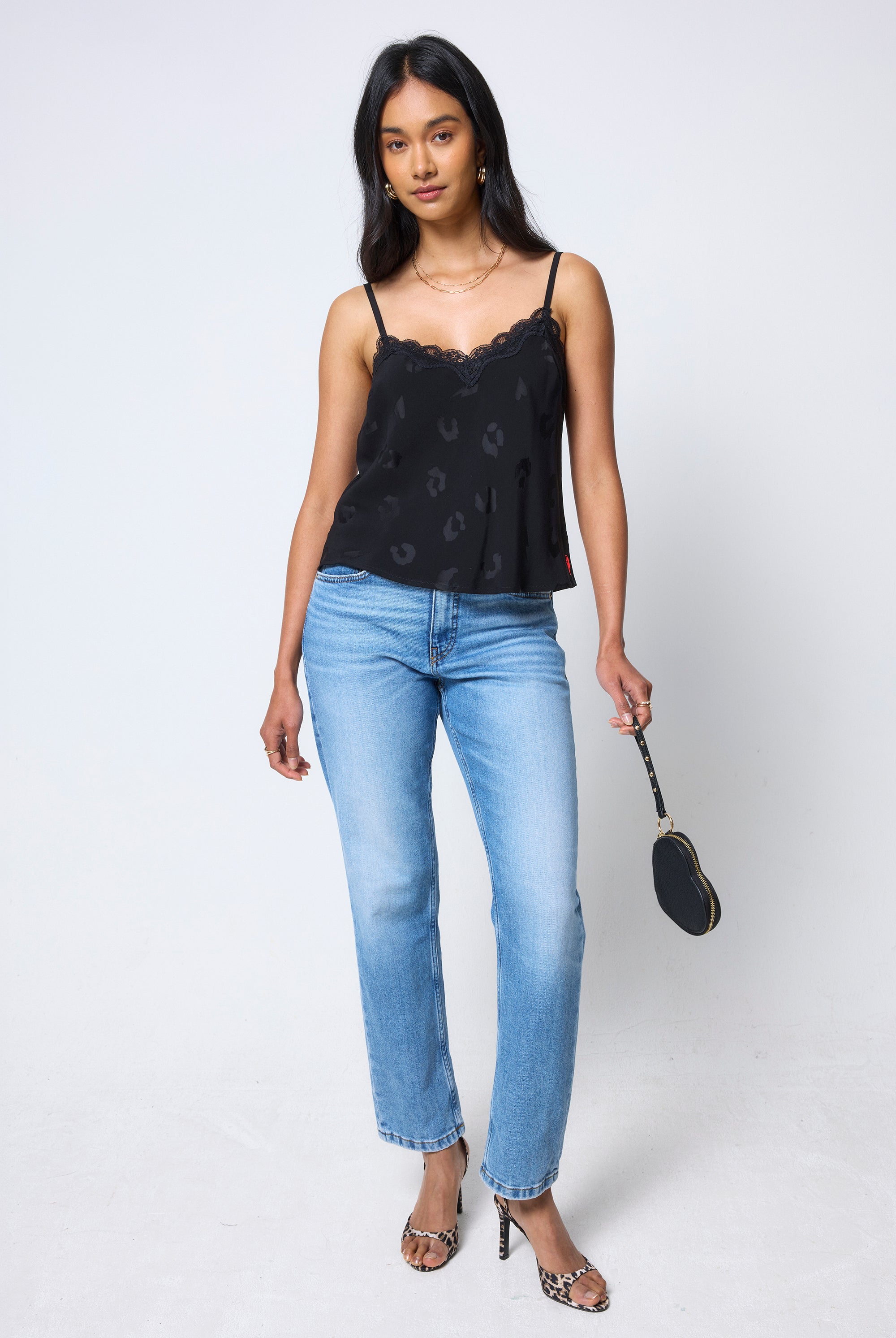 Scamp & Dude Black Jacquard Lace Trim Cami Top | Model wearing a black patterned cami top and blue jeans, holding a black heart shaped purse.