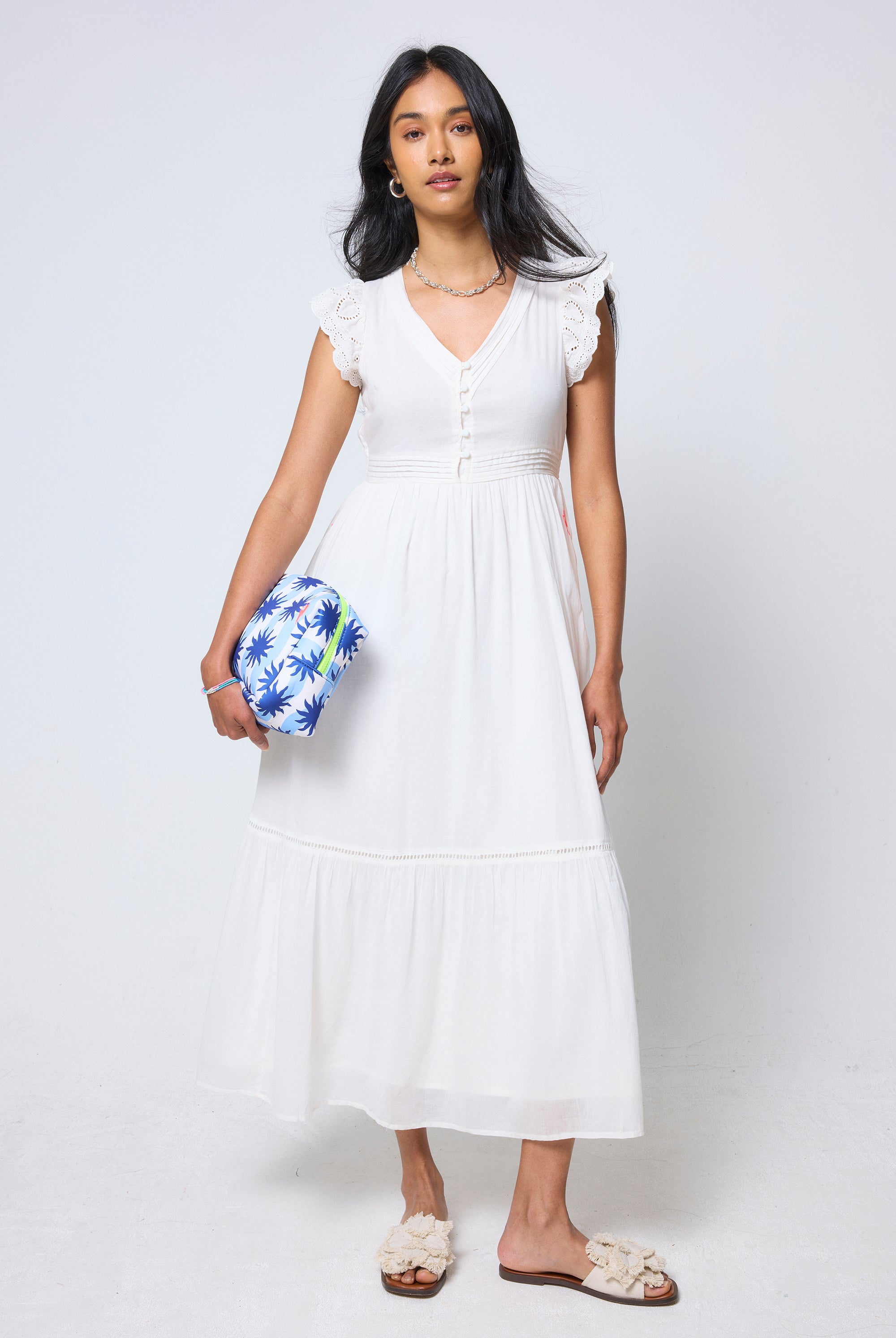 Scamp & Dude Cream Broderie Sleeve Pintuck Midi Dress | Model wearing a white pintuck midi dress holding a sunstar clutch with cream sandals.