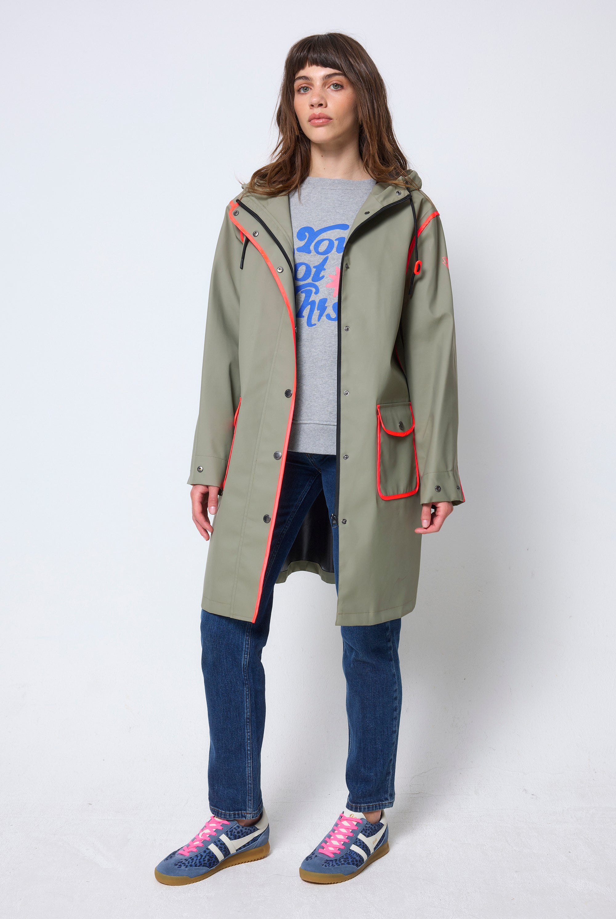 Scamp & Dude Khaki Raincoat | Model wearing a long green raincoat with neon coral details.