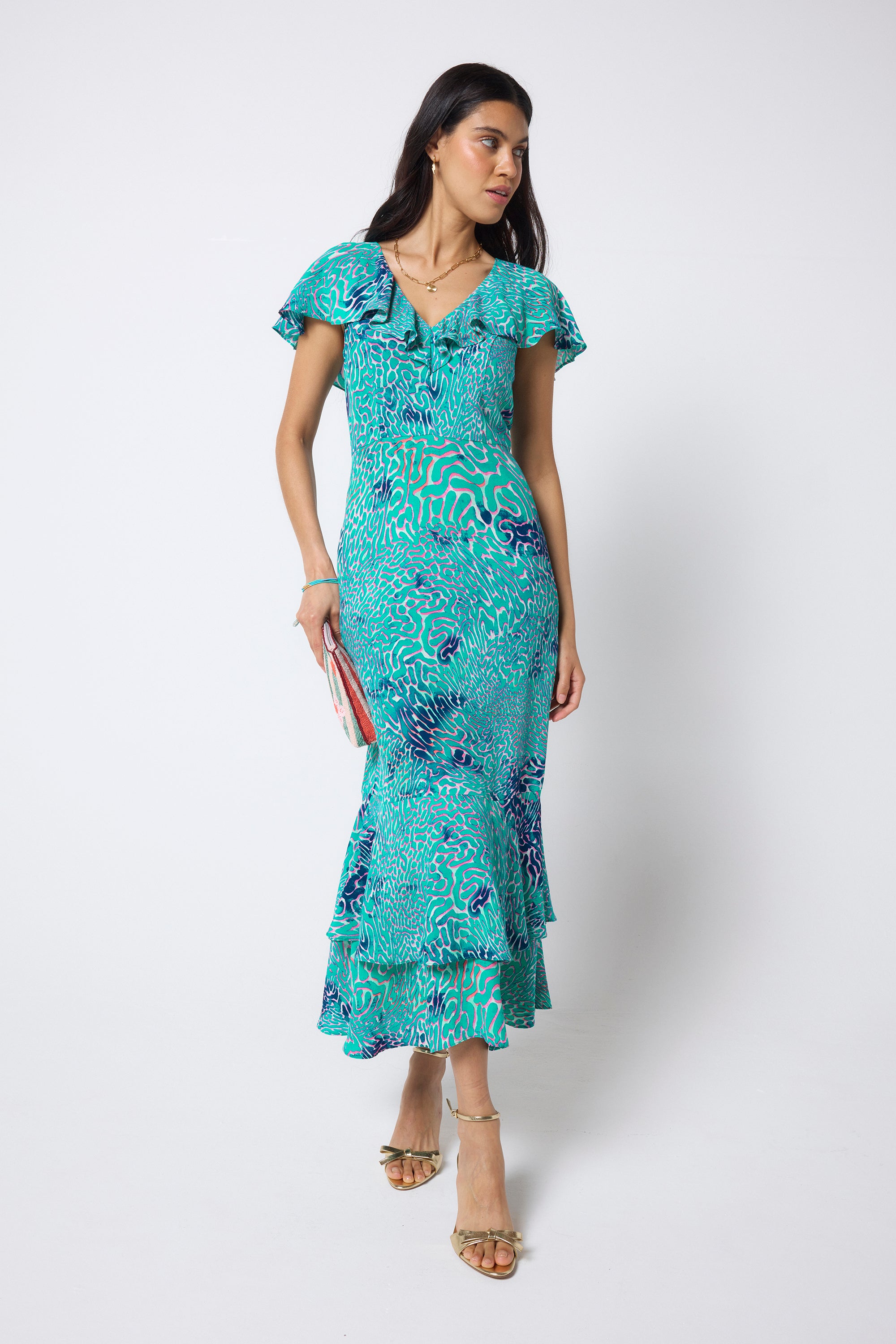 Scamp & Dude Blue Ocean Scales Cape Sleeve Midi Dress | Model wearing a blue printed midi dress with ruffle detail with gold high heels.