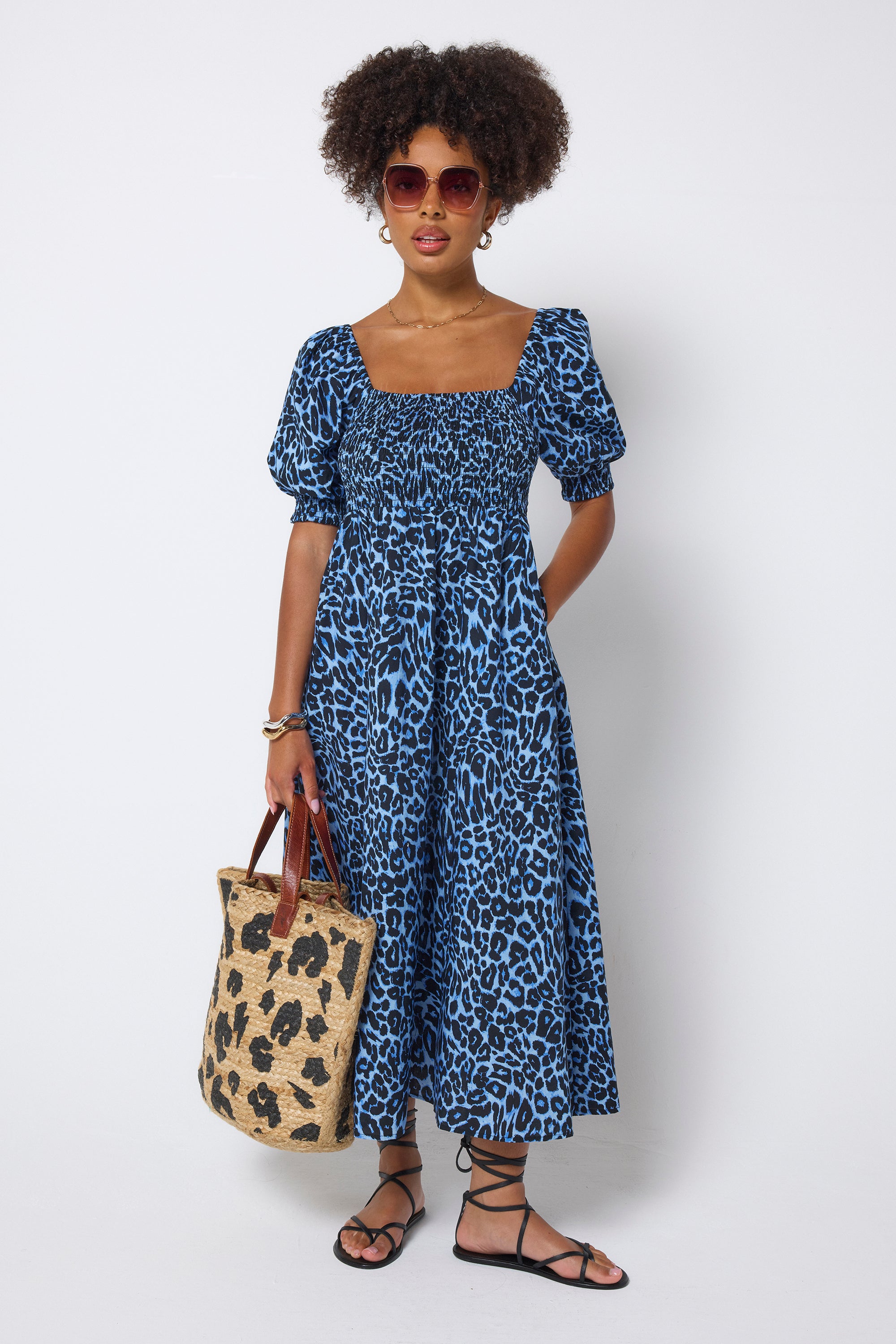 Scamp & Dude Blue Jaguar Wave Shirred Square Neck Midi Dress | Model wearing a blue jaguar print dress holding a leopard print straw bag.