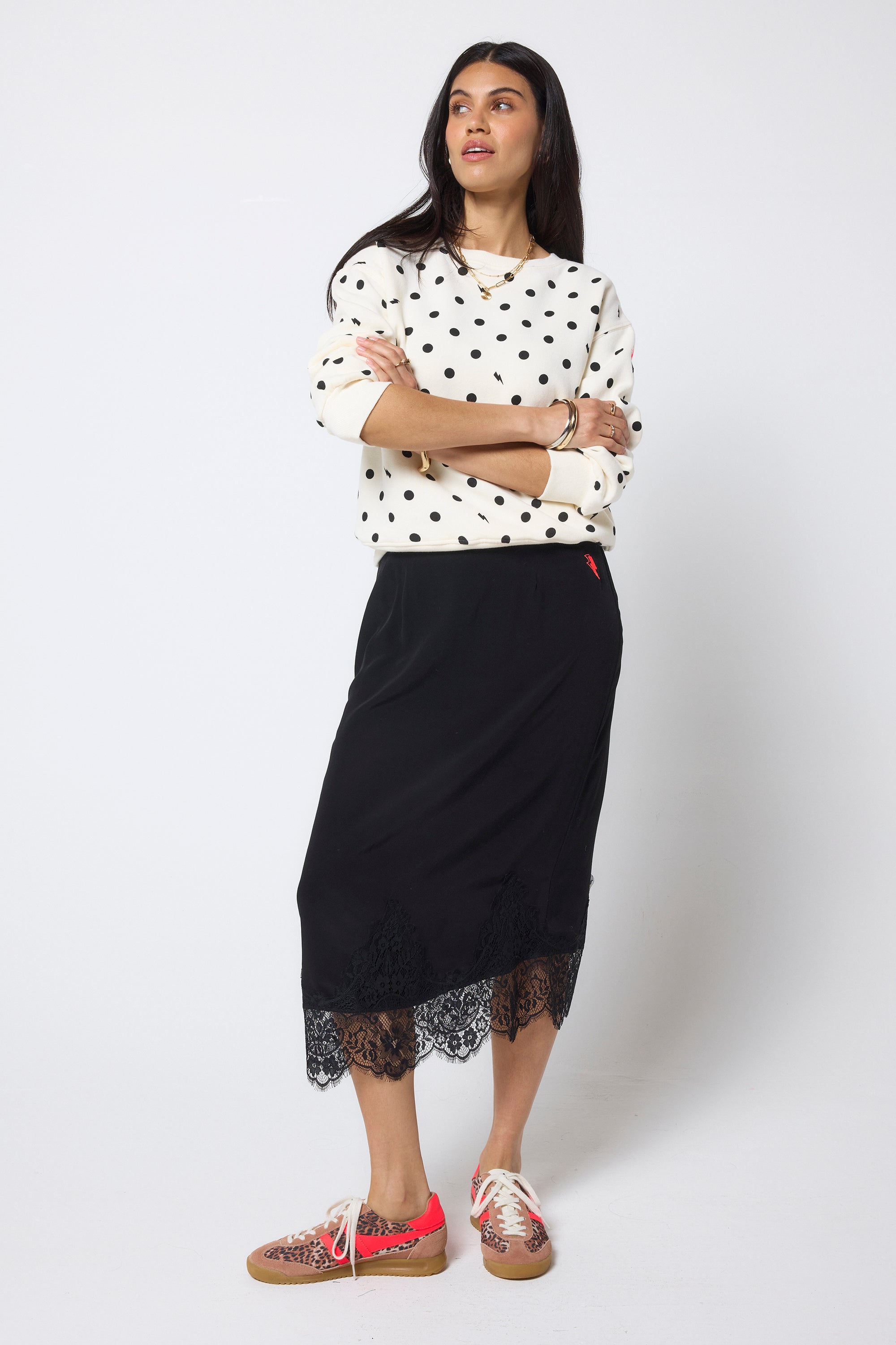 Scamp & Dude Ecru Polka Dot Bolt Ultimate Sweatshirt | Model wearing a black midi skirt with a scalloped lace hem, paired with an ecru long-sleeve sweatshirt with black polka dots.