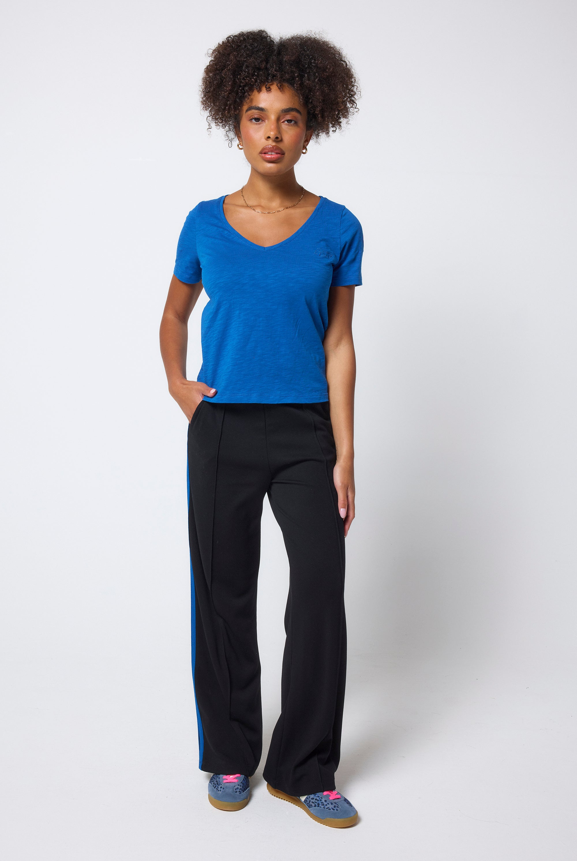 Scamp & Dude Cobalt Blue V-Neck T-Shirt | Model wearing a blue shirt and black wide leg trousers on a white background.