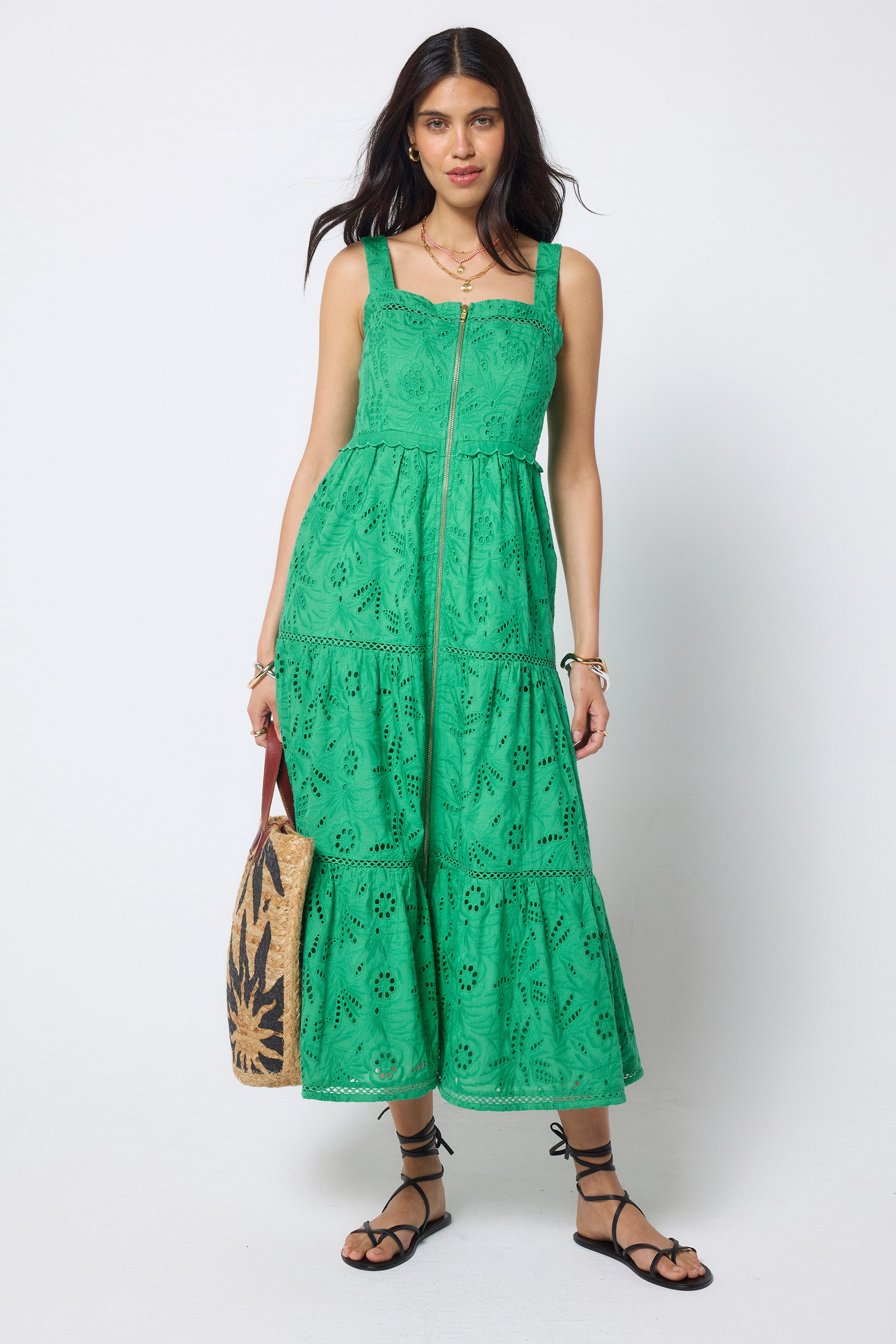 Scamp and Dude Green Broderie Zip Detail Midi Sundress | Model wearing a green broderie zip front midi dress with black sandals and sunglasses, holding a sun print straw bag.