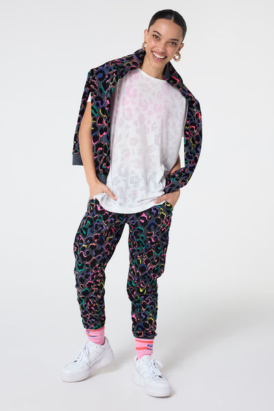 Scamp and Dude Grey with Rainbow Shadow Leopard and Lightning Bolt Cosy Joggers | Model wearing grey joggers featuring rainbow shadow leopard print paired with a white t shirt and a matching sweatshirt thrown over her shoulders.