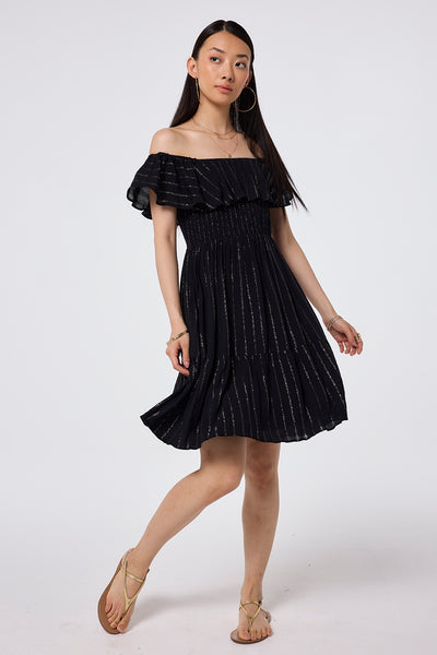 Scamp and Dude Black Lurex Short Bardot Dress | Model wearing a black short bardot dress with a lurex stripe detail paired with gold sandals.