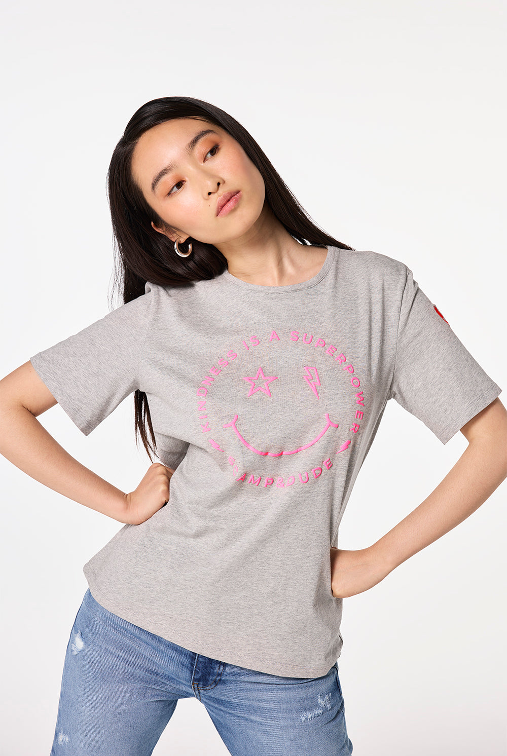 Scamp and Dude Grey Marl Smiley Face T-Shirt | Model wearing grey marl crew neck t-shirt featuring a pink smiley graphic print on the front.
