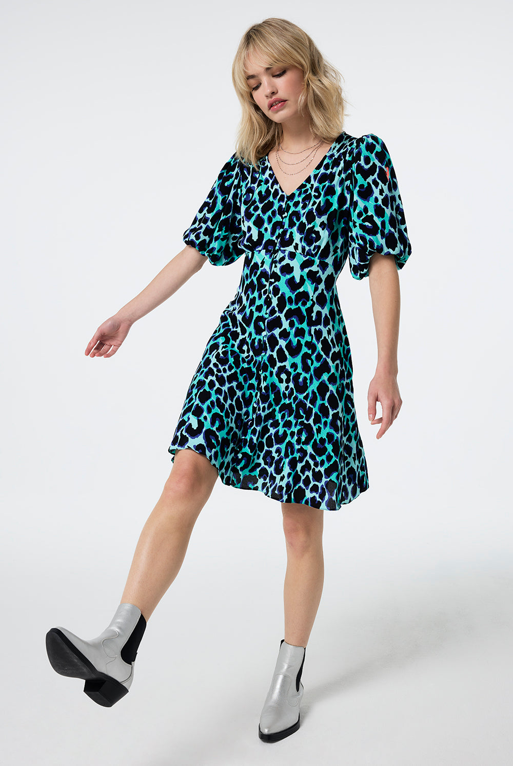 Scamp and Dude Turquoise with Black and Blue Shadow Leopard Puff Sleeve Short Tea Dress | Model wearing a turquoise short puff sleeve tea dress with black and blue shadow leopard print paired with silver boots.