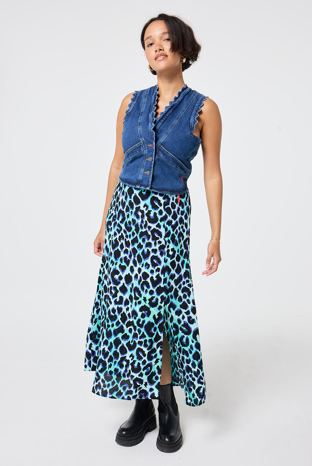 Scamp and Dude Turquoise with Black and Blue Shadow Leopard Split Front Skirt | Model wearing a scallop detail denim waistcoat paired with a turquoise midi skirt with black and blue leopard print.