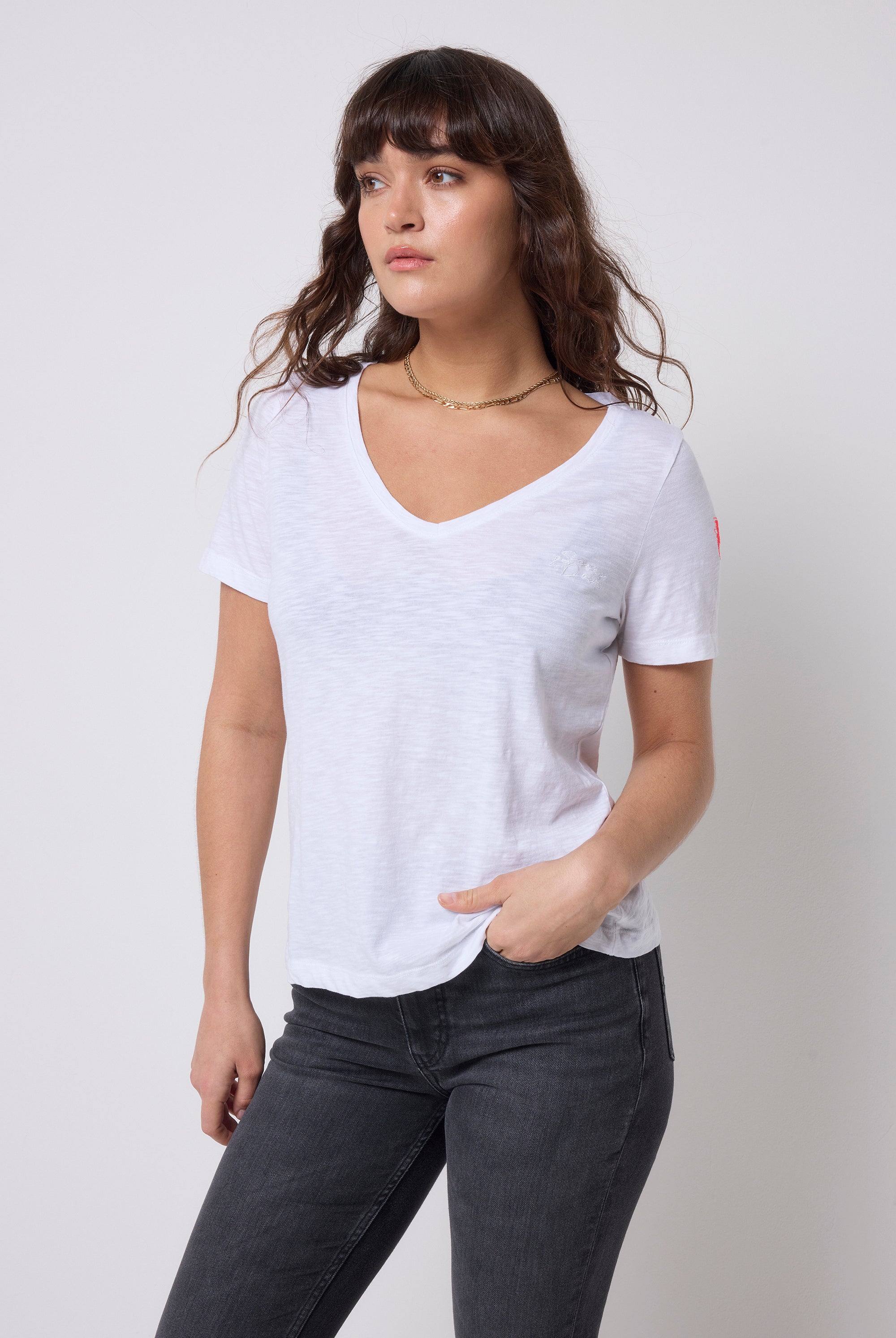 Scamp & Dude White V-Neck T-Shirt | Model wearing a white t-shirt and dark jeans with gold jewellery.