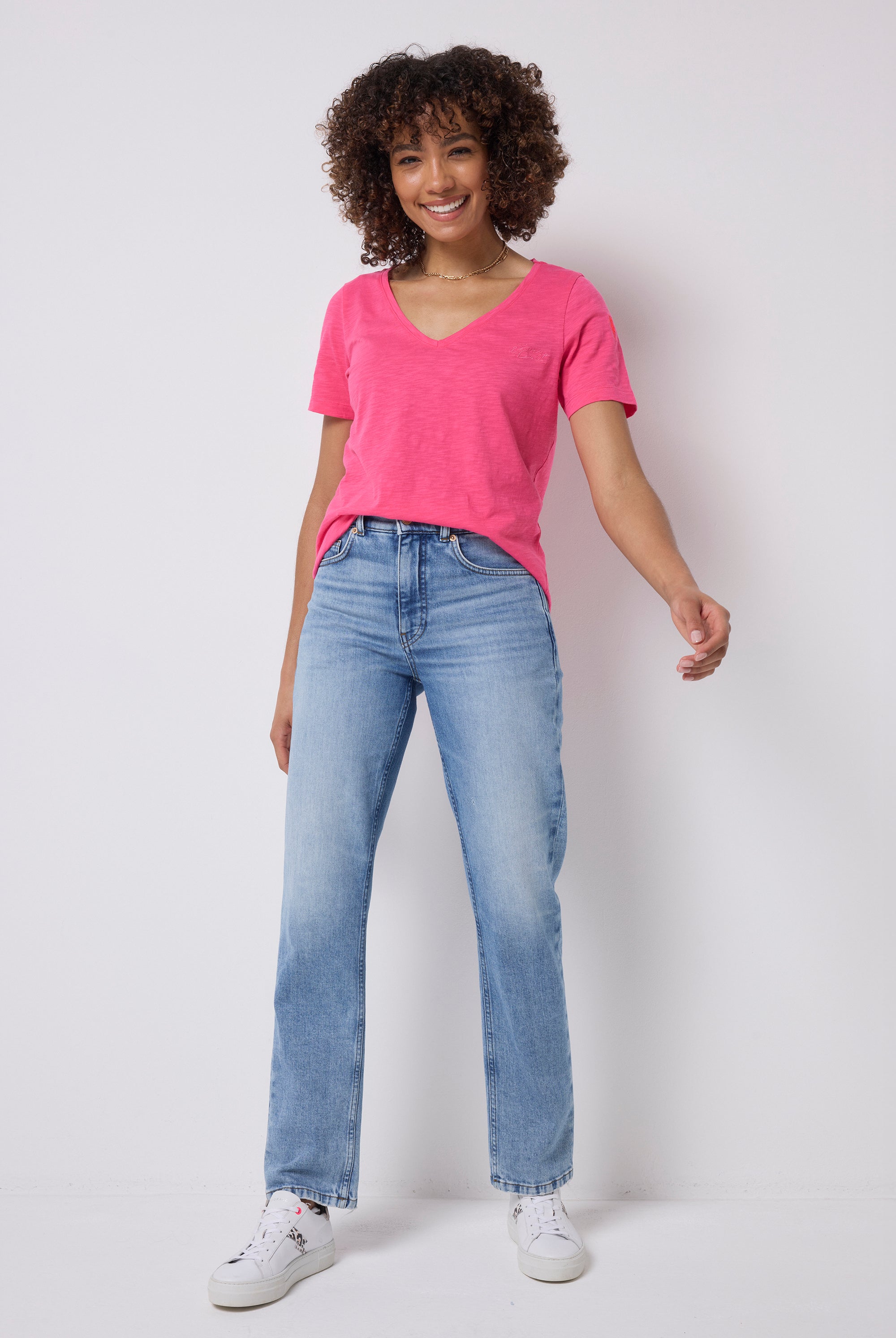 Scamp & Dude Pink V-Neck T-Shirt | Model wearing a pink v-neck t-shirt shirt with blue jeans and white trainers.