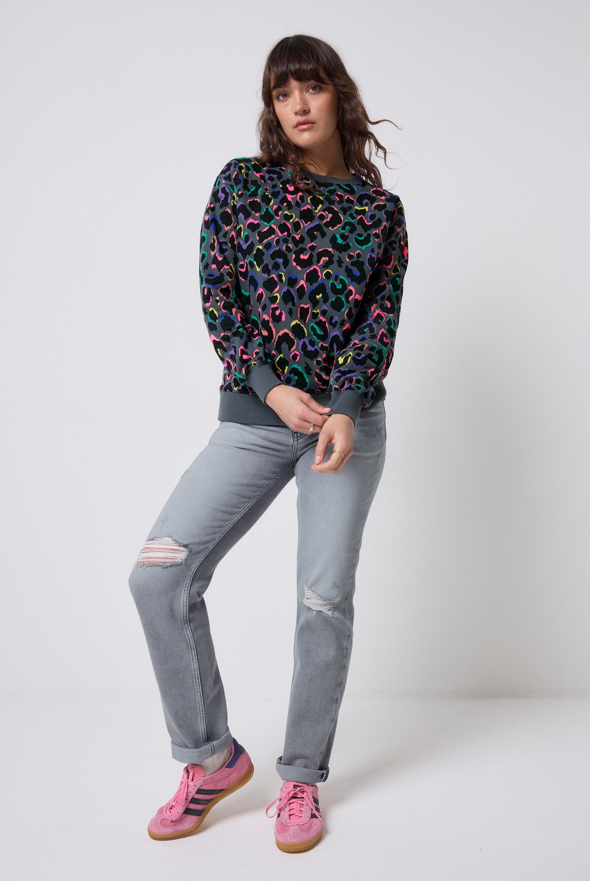 Scamp and Dude Grey with Rainbow Shadow Leopard Classic Sweatshirt | Model wearing a grey crew neck sweatshirt in a classic fit with rainbow shadow leopard print, paired with grey distressed jeans.