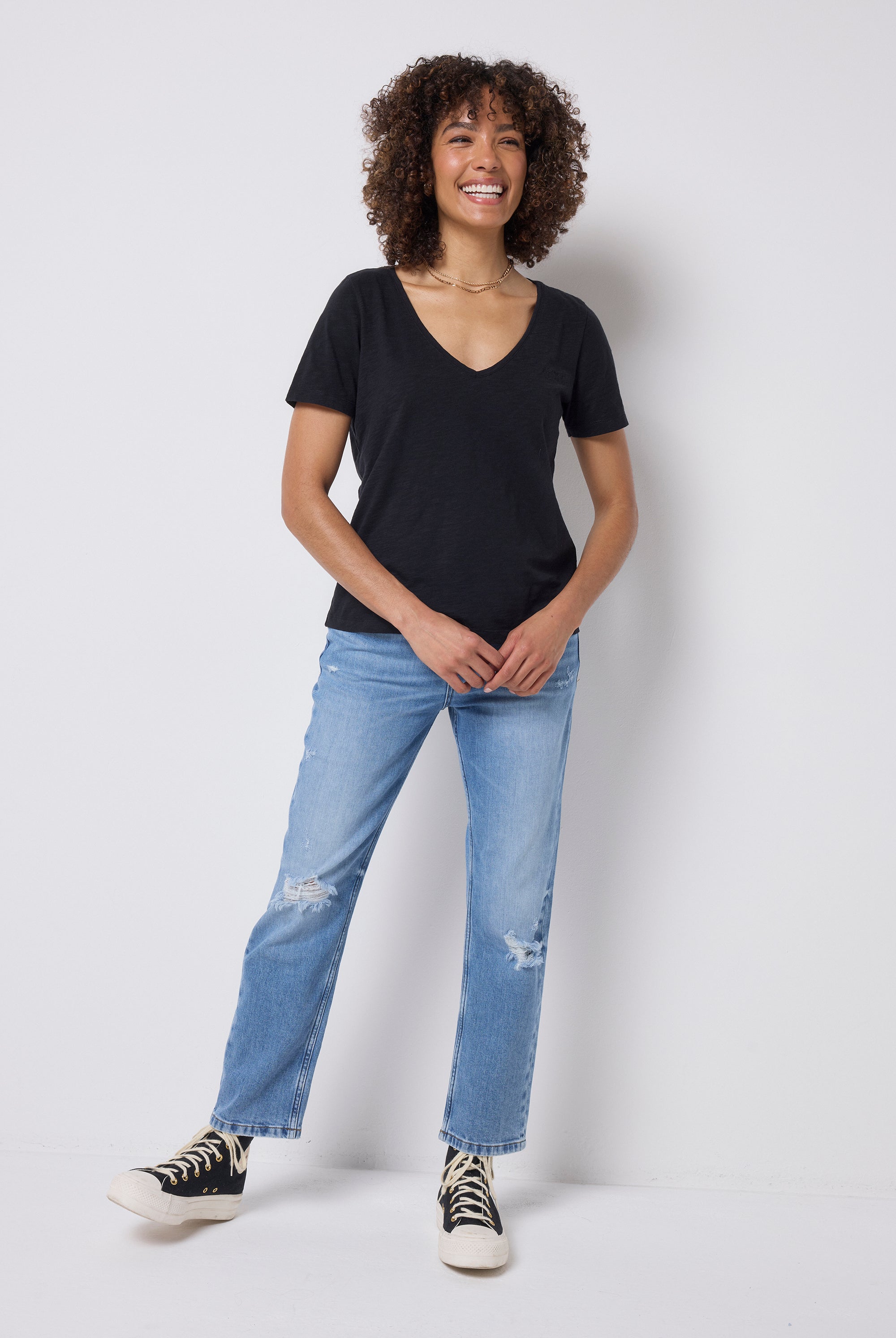 Scamp & Dude Black V-Neck T-Shirt | Model wearing a black t-shirt and blue distressed jeans with black trainers.