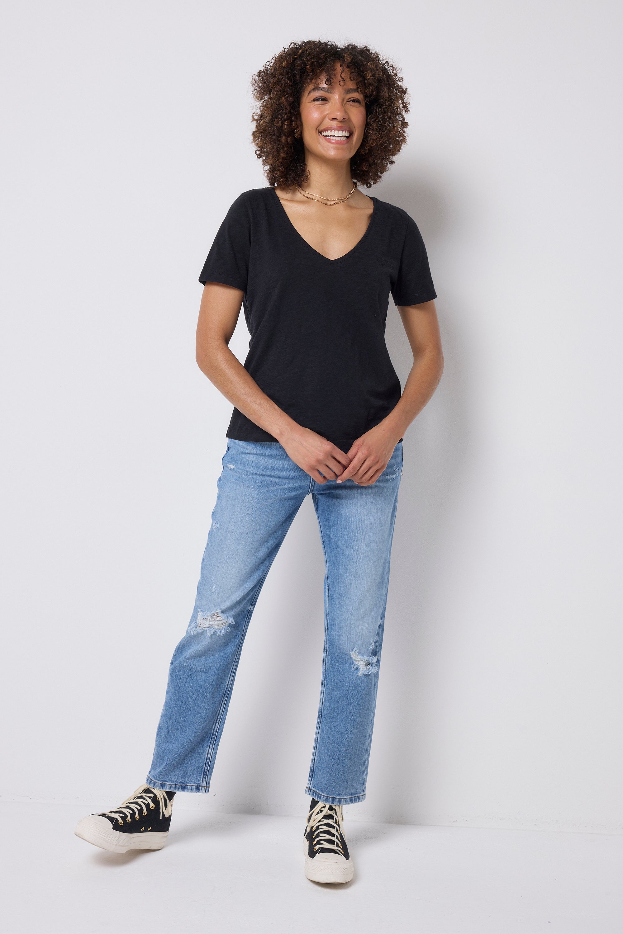 Scamp & Dude Black V-Neck T-Shirt | Model wearing a black t-shirt and blue distressed jeans with black trainers.