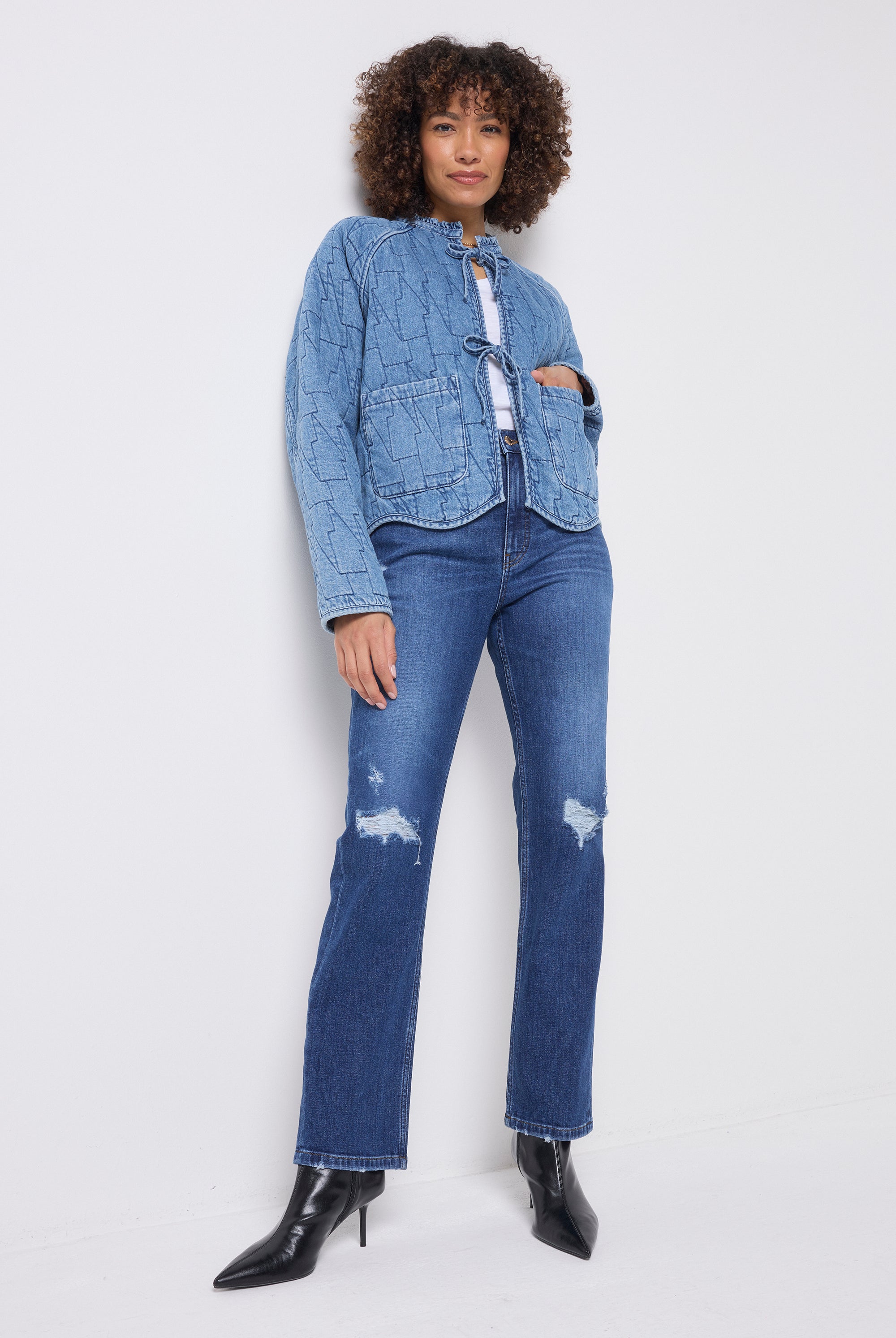 Scamp & Dude Mid Indigo Wash Distressed Boyfriend Jeans | Model wearing a pair of dark blue distressed jeans with a lighter denim tie front jacket and black boots.