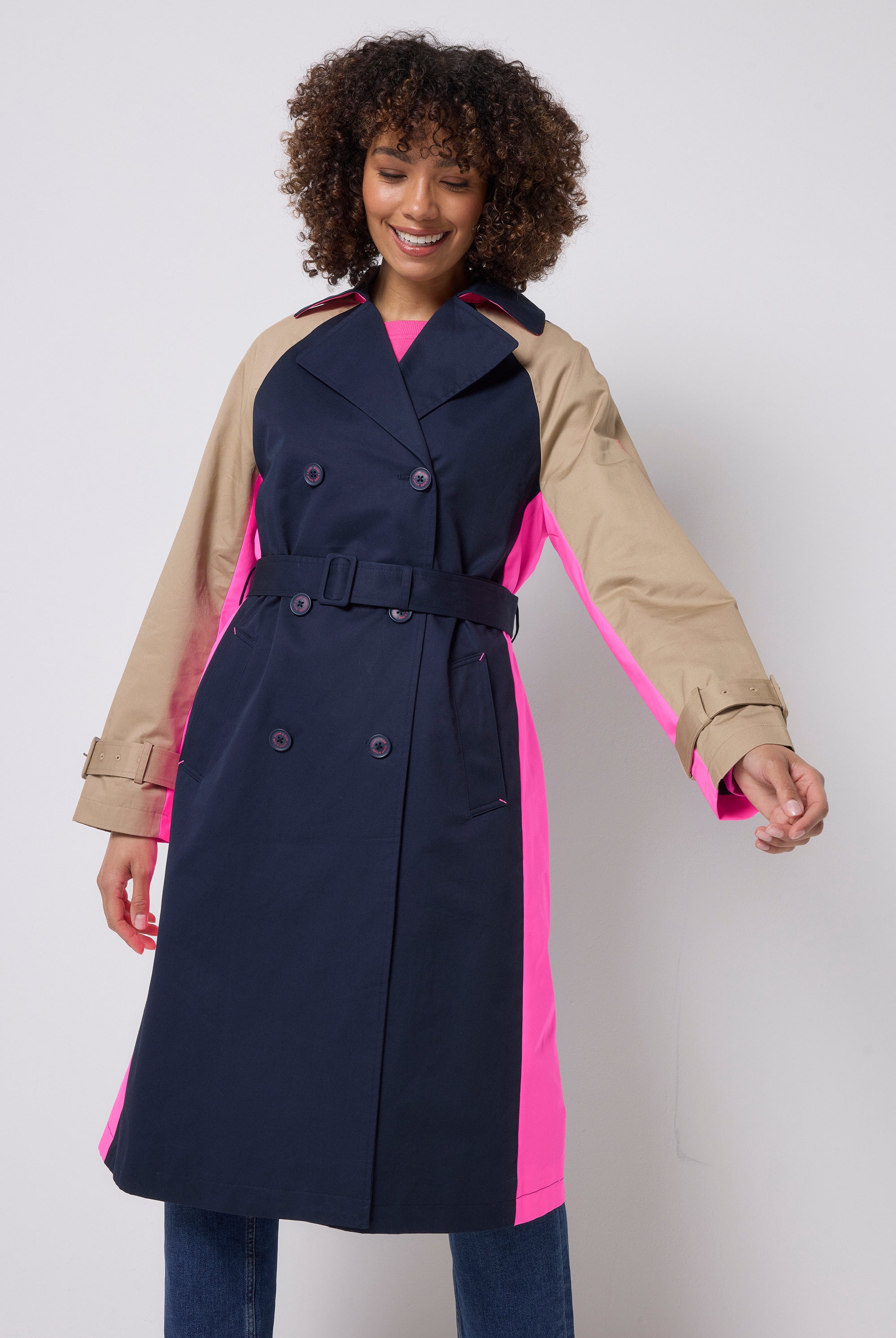 Scamp & Dude Navy and Stone Colourblock Trench Coat | Model is wearing a navy and stone colourblock trench coat with pink details. Worn with dark blue jeans.