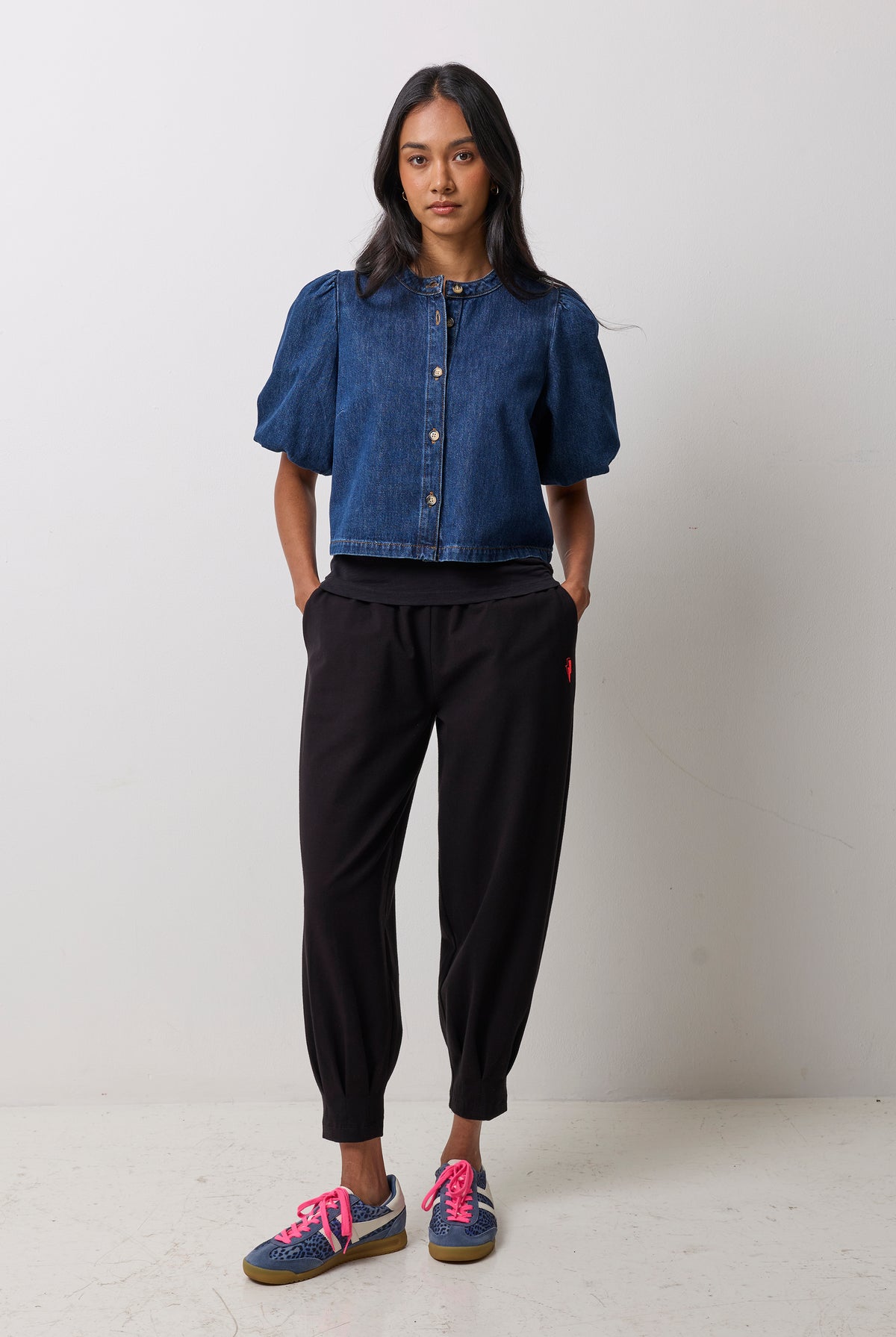 Scamp & Dude Black Barrel Joggers | Model wearing a denim button front puff sleeve top with black jogger pants and navy cheetah Gola trainers.