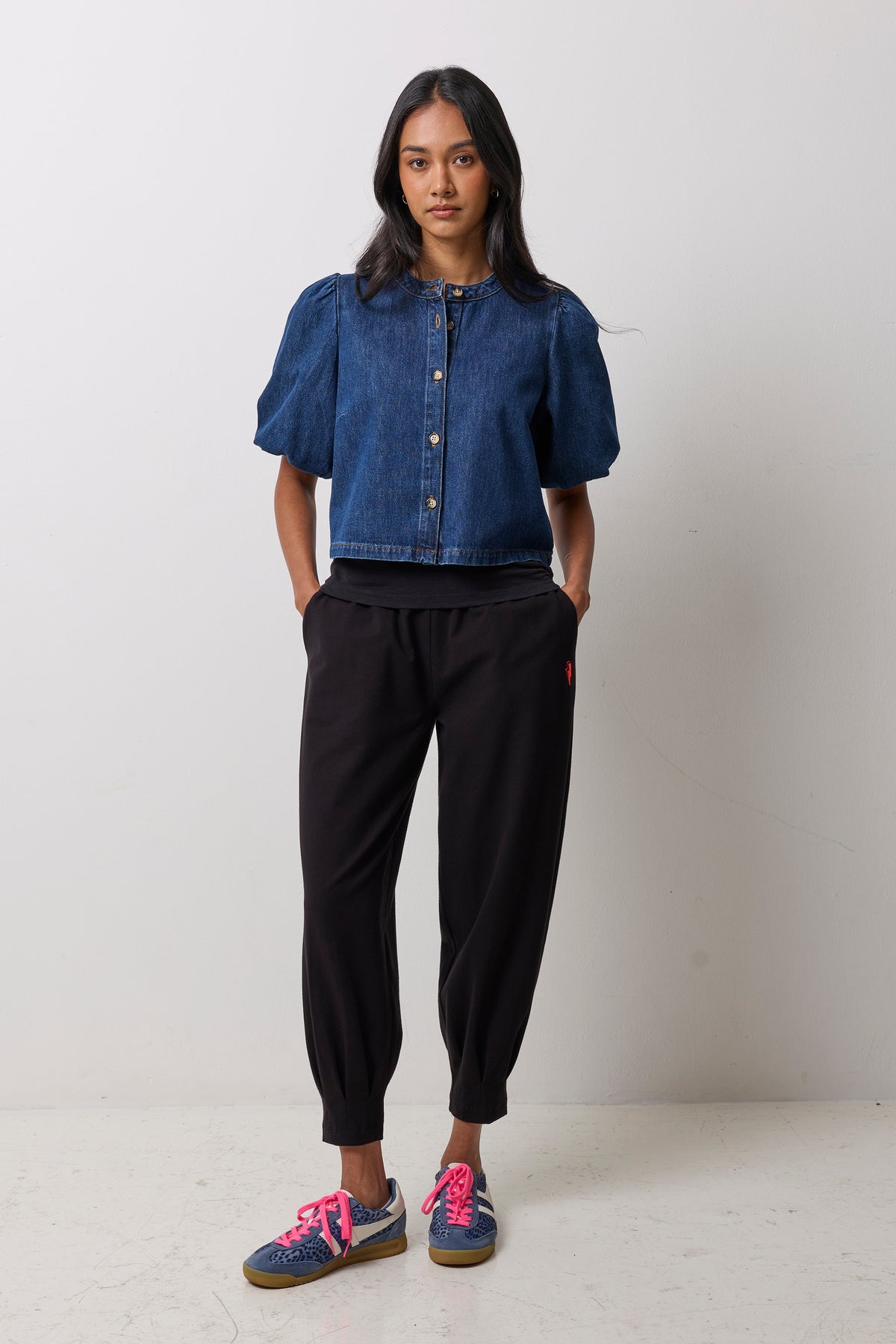 Scamp & Dude Black Barrel Joggers | Model wearing a denim button front puff sleeve top with black jogger pants and navy cheetah Gola trainers.