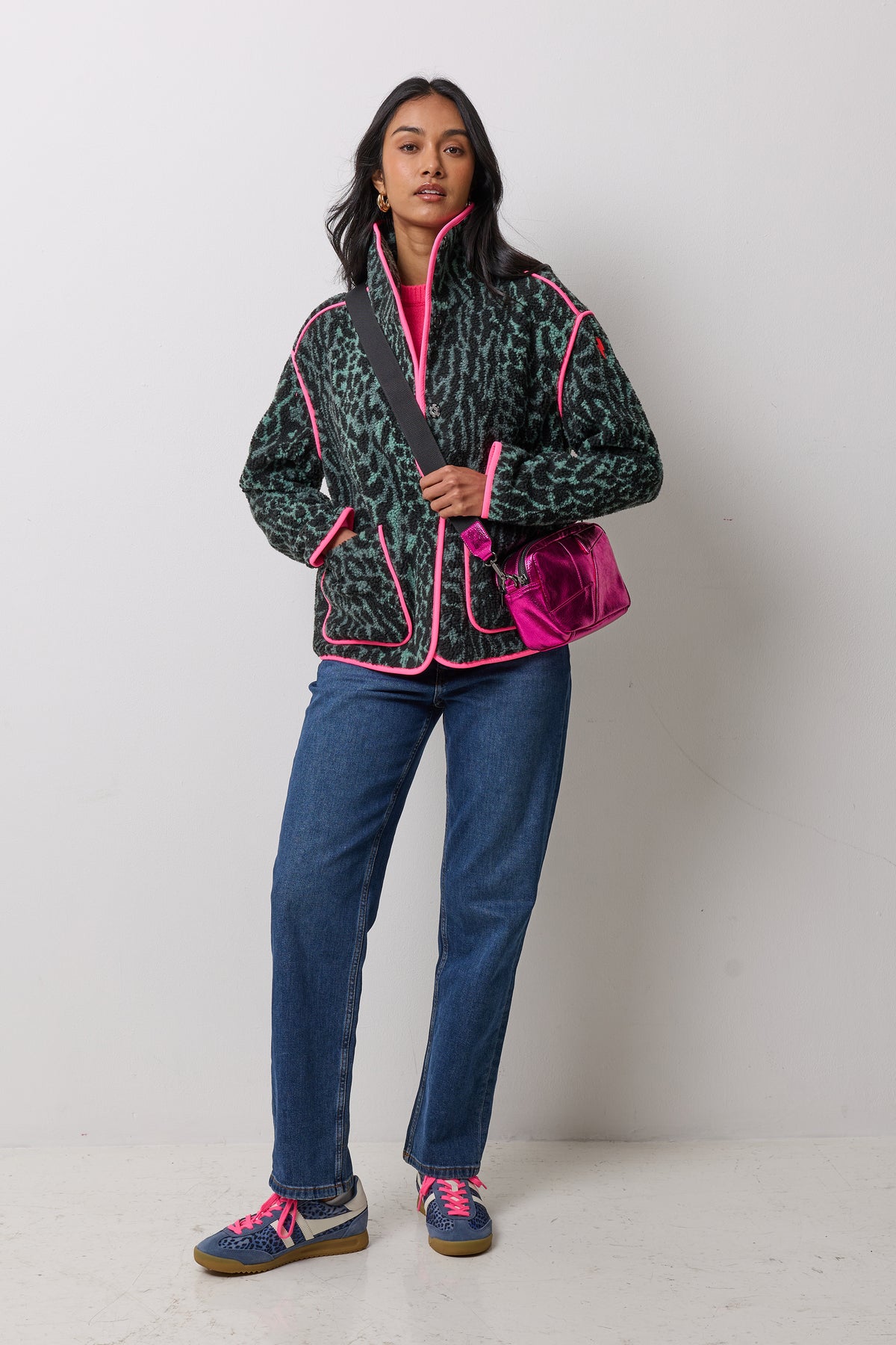 Scamp & Dude Green and Black Cloud Leopard Fleece Jacket | Model wearing a khaki cloud leopard print fleece with a pink bag and blue jeans.