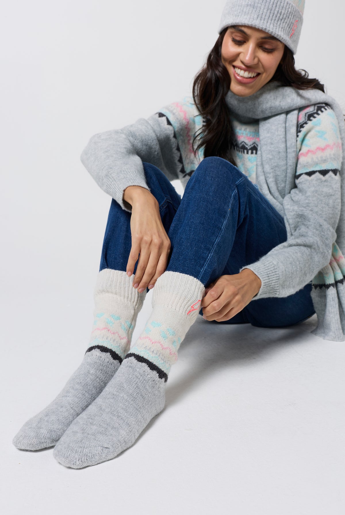 Scamp & Dude Grey Marl Fairisle Cosy Socks | Model wearing a pair of blue jeans with a fairisle knit jumper and matching hat, scarf and gloves.