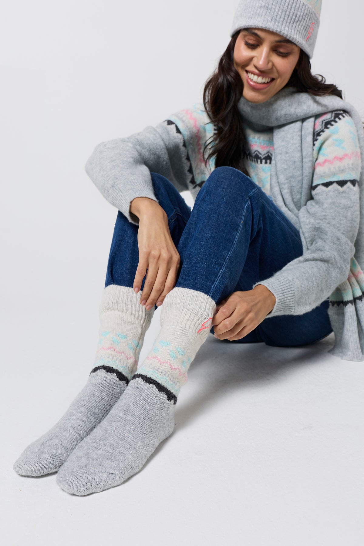 Scamp & Dude Grey Marl Fairisle Cosy Socks | Model wearing a pair of blue jeans with a fairisle knit jumper and matching hat, scarf and gloves.