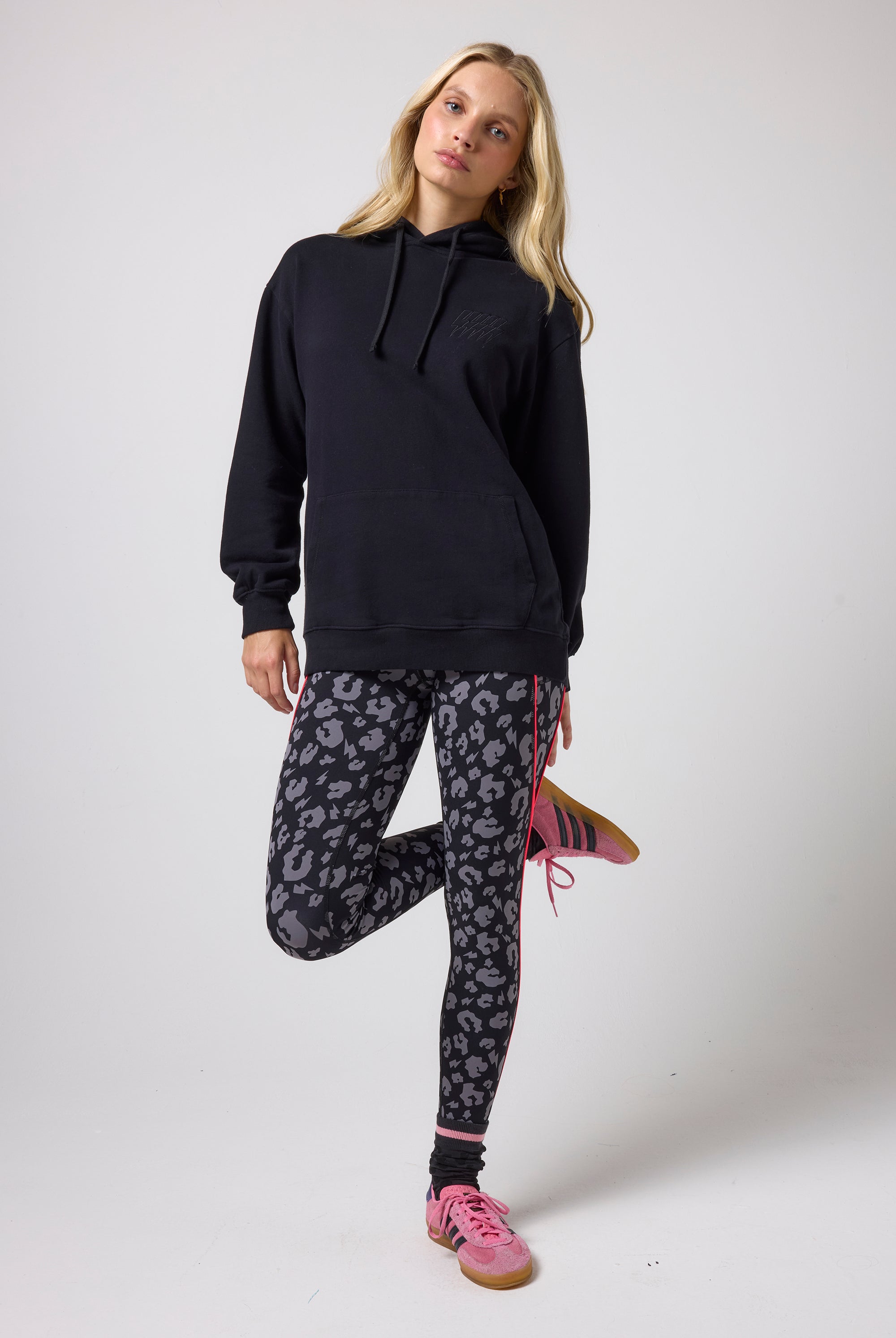 Scamp & Dude Black Multi Neon Bolt Longline Hoodie | Model wearing a black hoodie and patterned leggings on a white background.