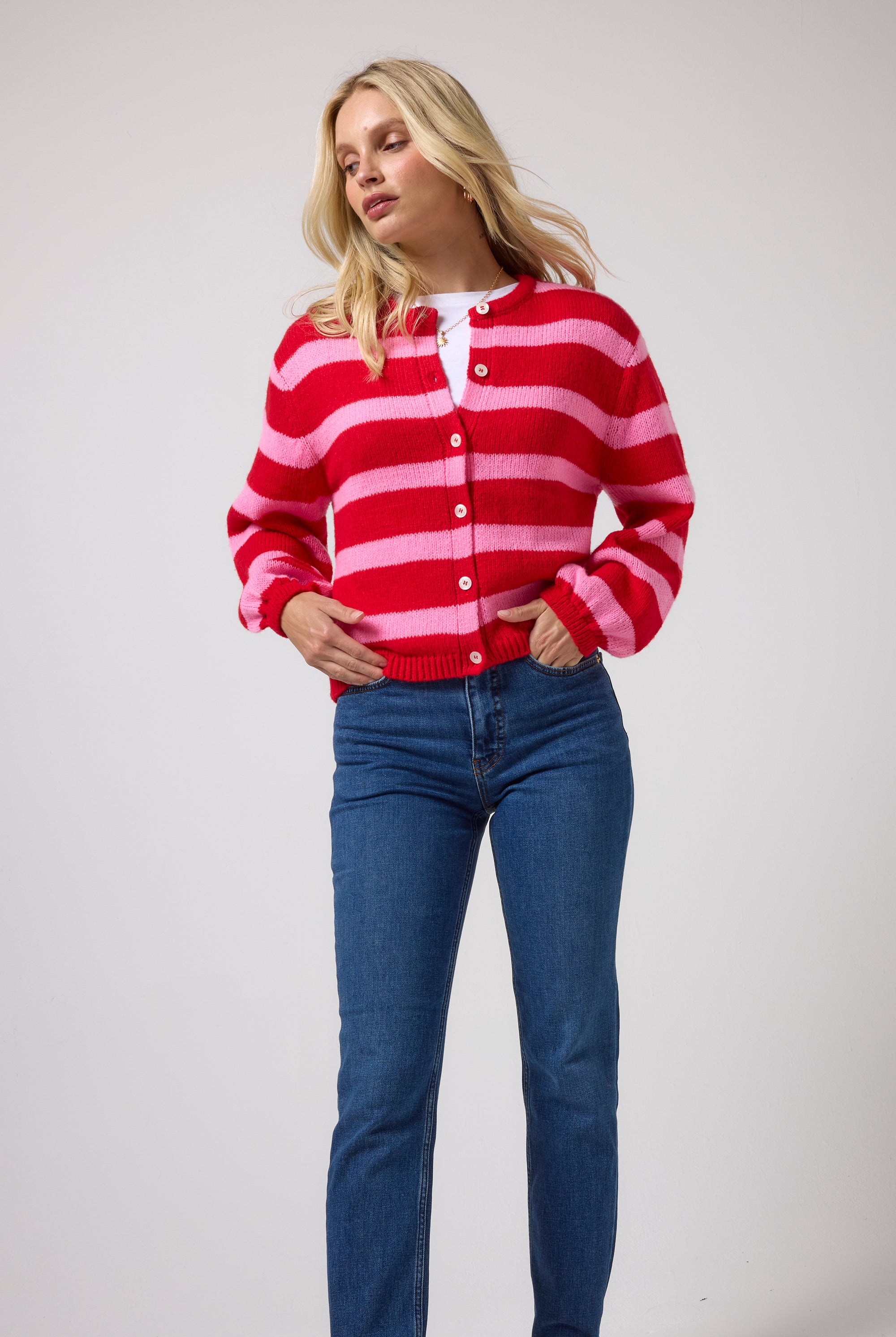 Scamp & Dude Red with Pink Stripe Cardigan | Model wearing a red and pink striped button-up cardigan with blue jeans.
