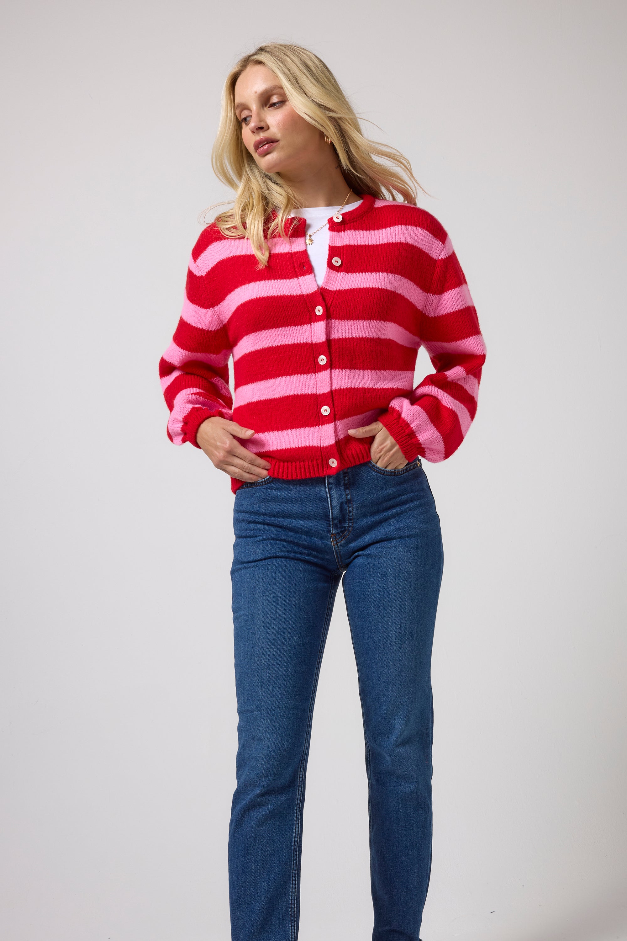 Scamp & Dude Red with Pink Stripe Cardigan | Model wearing a red and pink striped button-up cardigan with blue jeans.