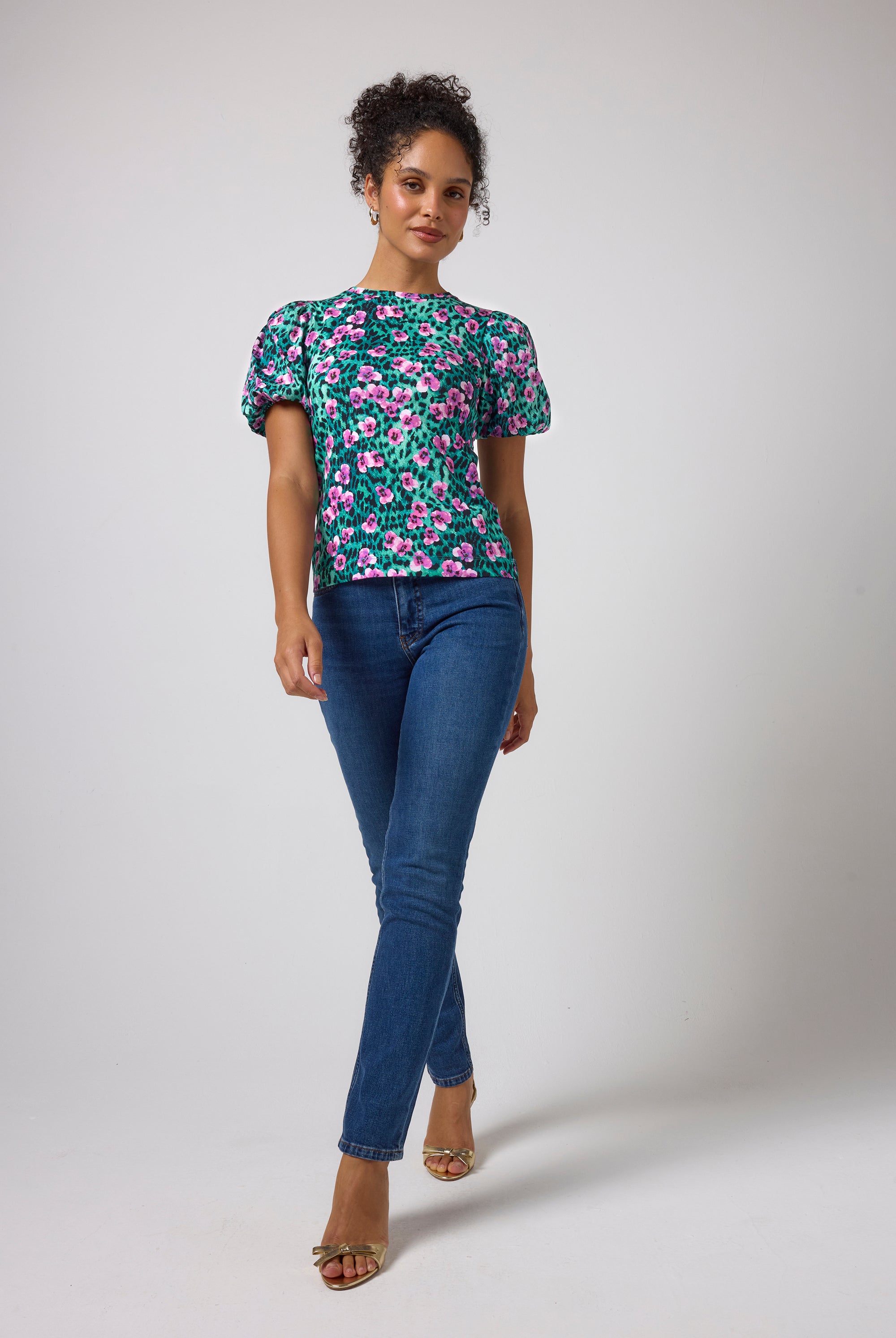 Scamp & Dude Turquoise Paradise Cheetah Puff Sleeve T-Shirt | Model wearing a short-sleeve floral print top with puff sleeves and blue boyfriend jeans.