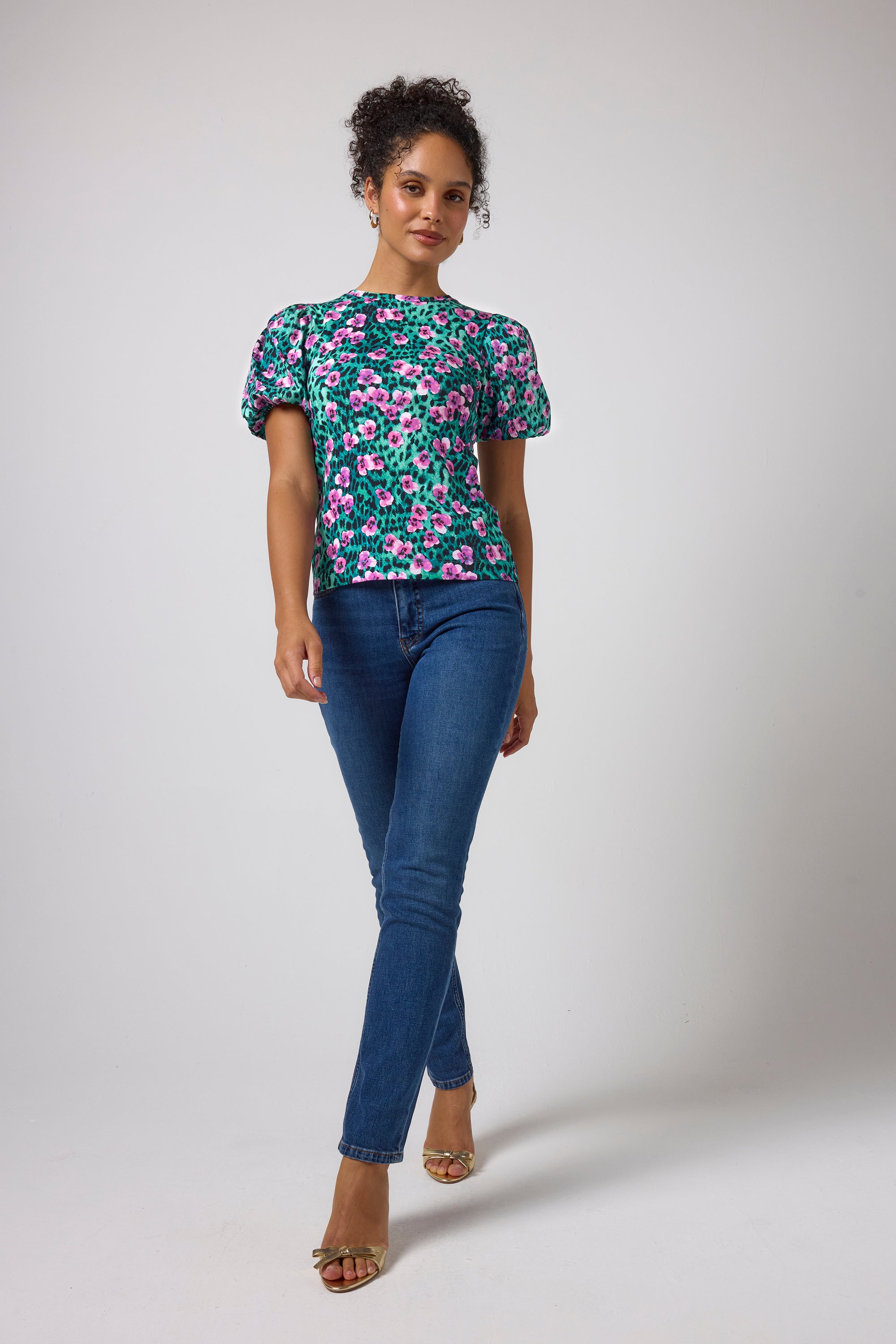 Scamp & Dude Turquoise Paradise Cheetah Puff Sleeve T-Shirt | Model wearing a short-sleeve floral print top with puff sleeves and blue boyfriend jeans.