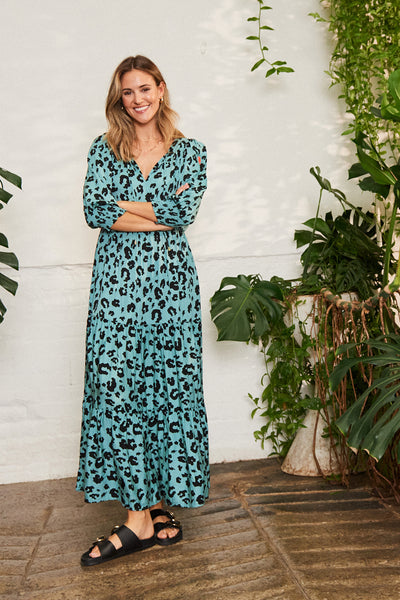 Scamp and Dude Green with Black Floral Leopard Maxi Dress | Blonde woman wearing long green dress with black leopard print and black sandals against white background with plants
