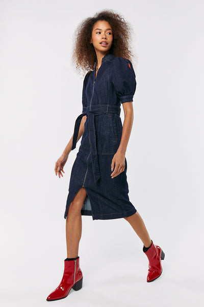 Scamp and Dude Rinse Wash Zip Detail Denim Dress | Model with curly hair wearing a dark denim wash dress with red pointed heel boots