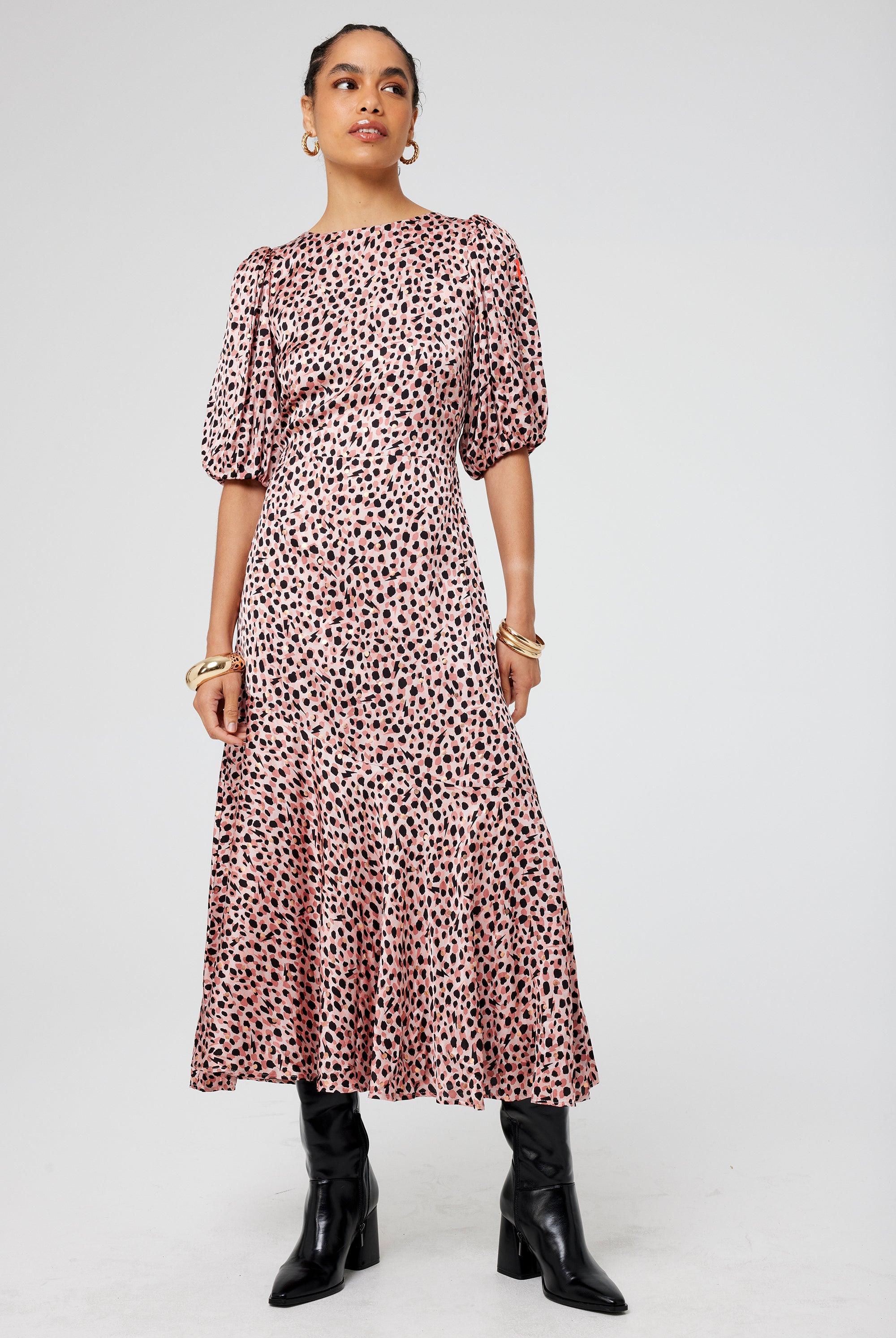 Scamp and Dude Neutral with Pink and Gold Foil Spot Cheetah Peplum Puff Sleeve Midi Dress | Model wearing a neutral puff sleeve midi dress featuring a peplum hem paired with black boots.