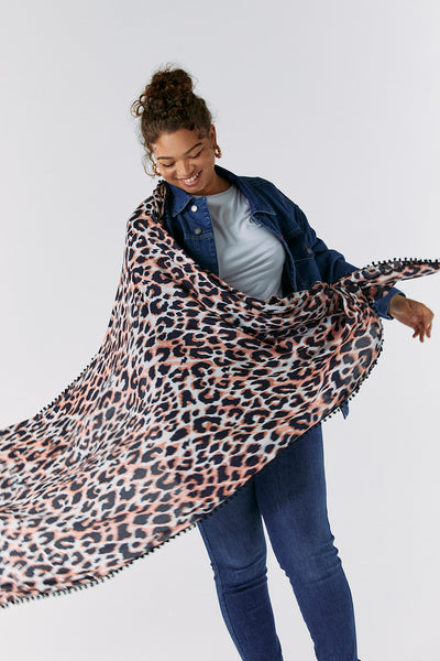 Scamp and Dude Mixed Neutral with Black Shadow Leopard Charity Super Scarf | Model smiling wearing matching denim jacket and jeans with leopard print scarf wrapped over shoulders