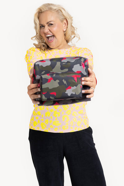 Scamp and Dude Scamp & Dude x Caroline Hirons Khaki with Pink Camo Cosmetic Bag | Caroline Hirons, a blonde lady smiling, holding the khaki bag wearing a yellow bag  