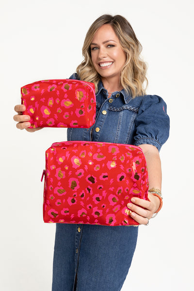 Scamp and Dude Scamp & Dude x Hannah Martin Red with Neon Pink and Gold Foil Snow Leopard Cosmetic Bag | Hannah Martin holding two red cosmetic bags with pink leopard print  
