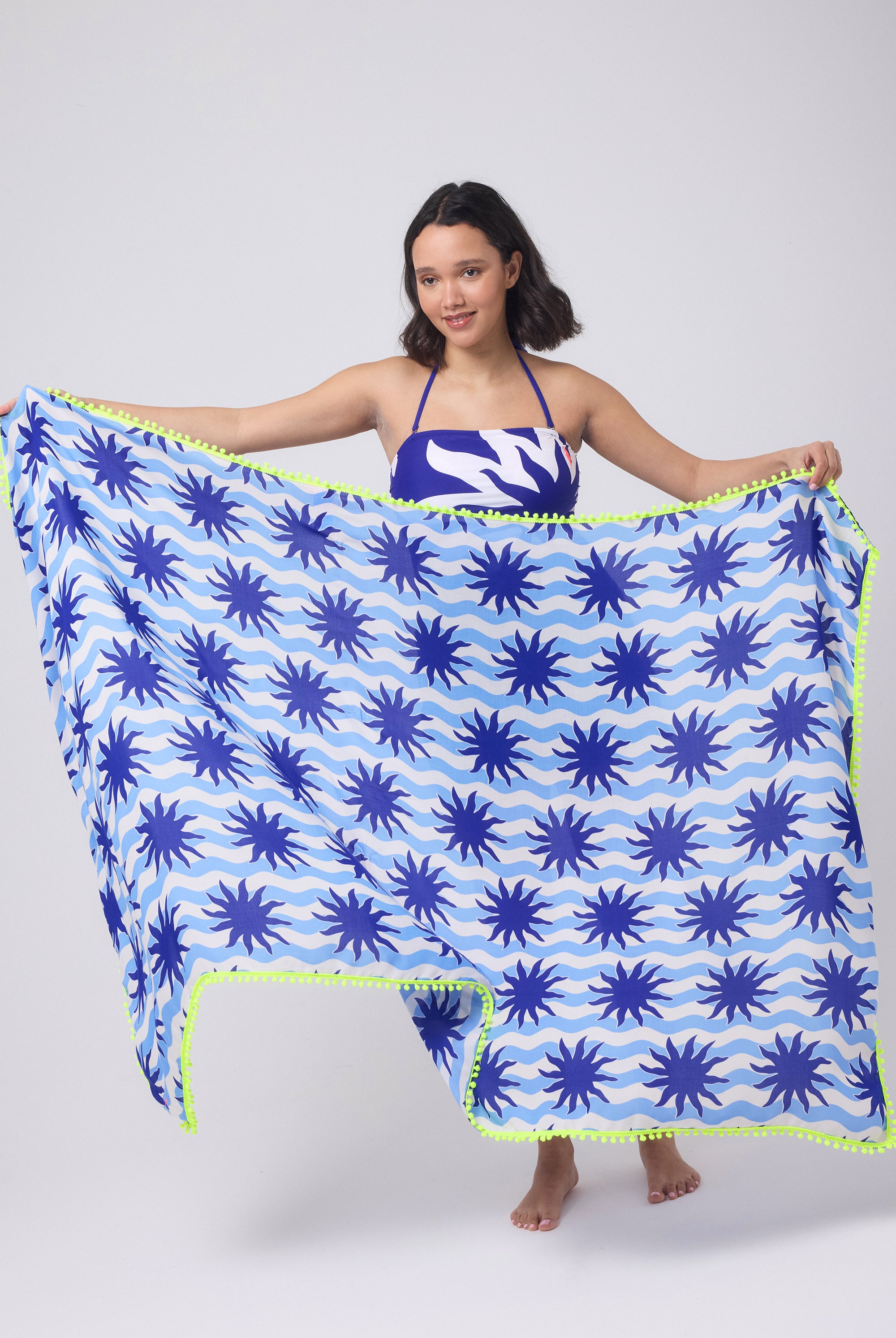 Scamp and Dude Blue with Cream Wiggle Sunstar Charity Super Scarf | Model holding a blue and white stripe super scarf with sun print detail. Worn with a matching swimsuit.