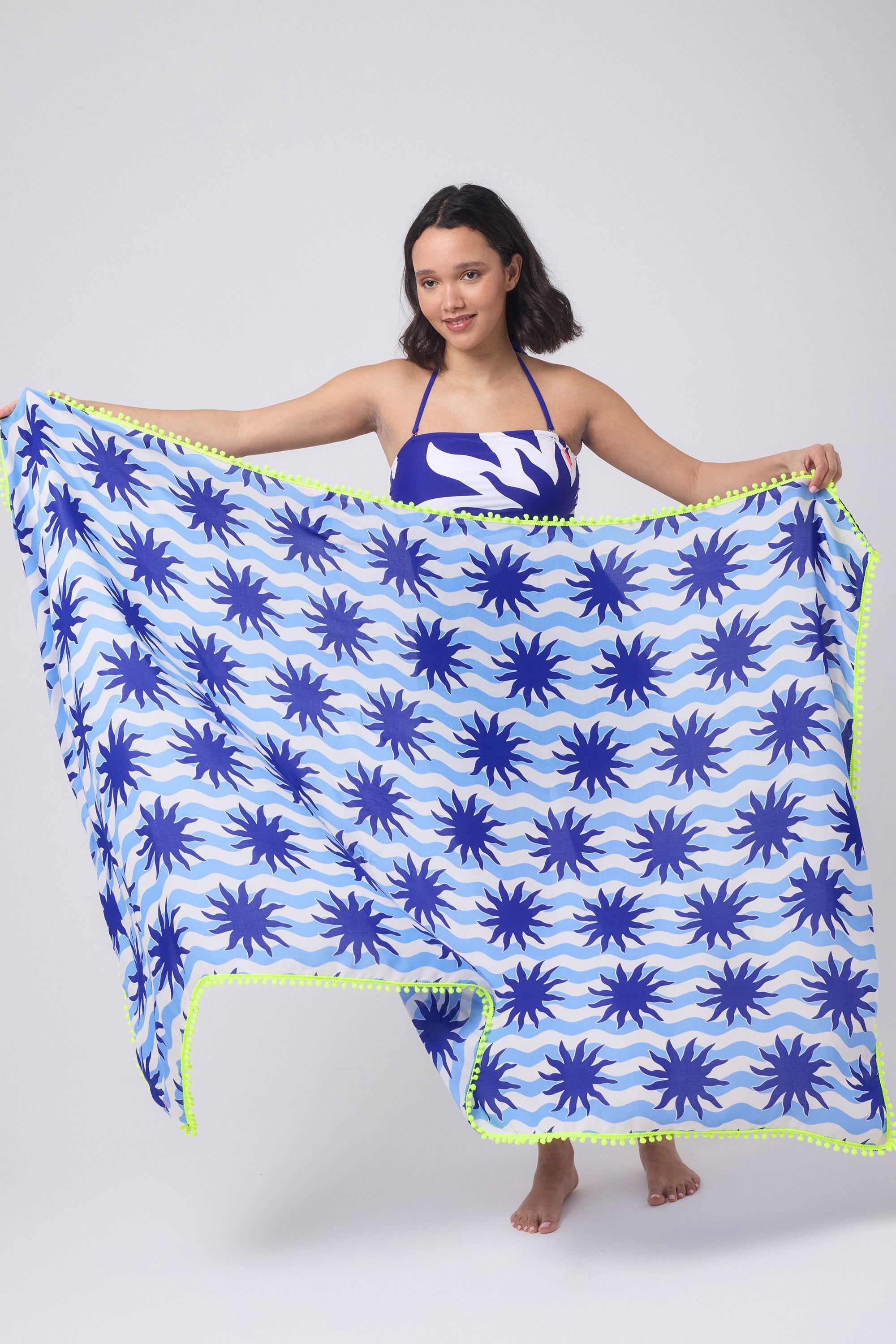 Scamp and Dude Blue with Cream Wiggle Sunstar Charity Super Scarf | Model holding a blue and white stripe super scarf with sun print detail. Worn with a matching swimsuit.