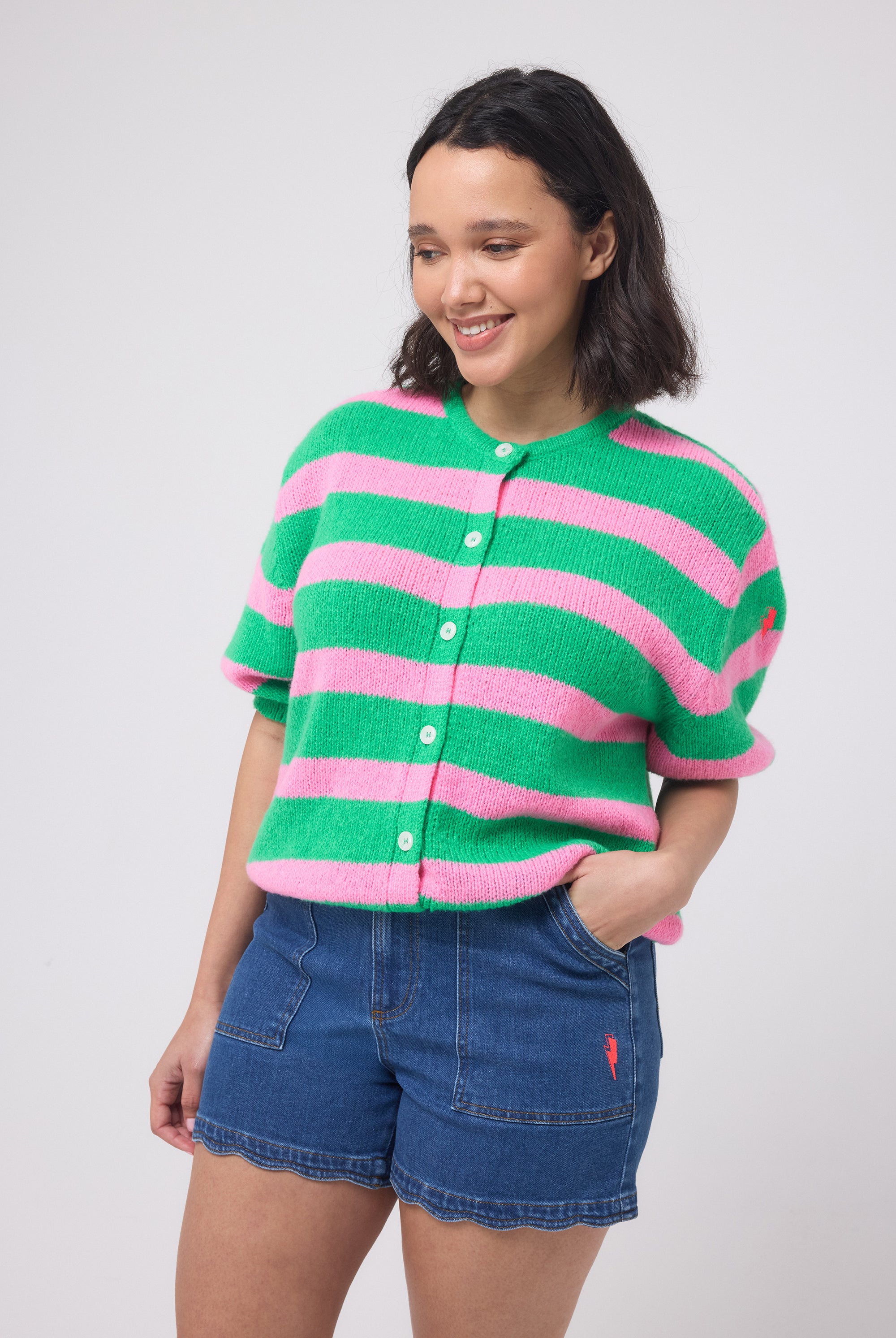 Scamp and Dude Green with Pink Stripe Short Sleeve Cardigan | Model wearing a short sleeve green and pink striped cardigan with dark blue denim shorts.
